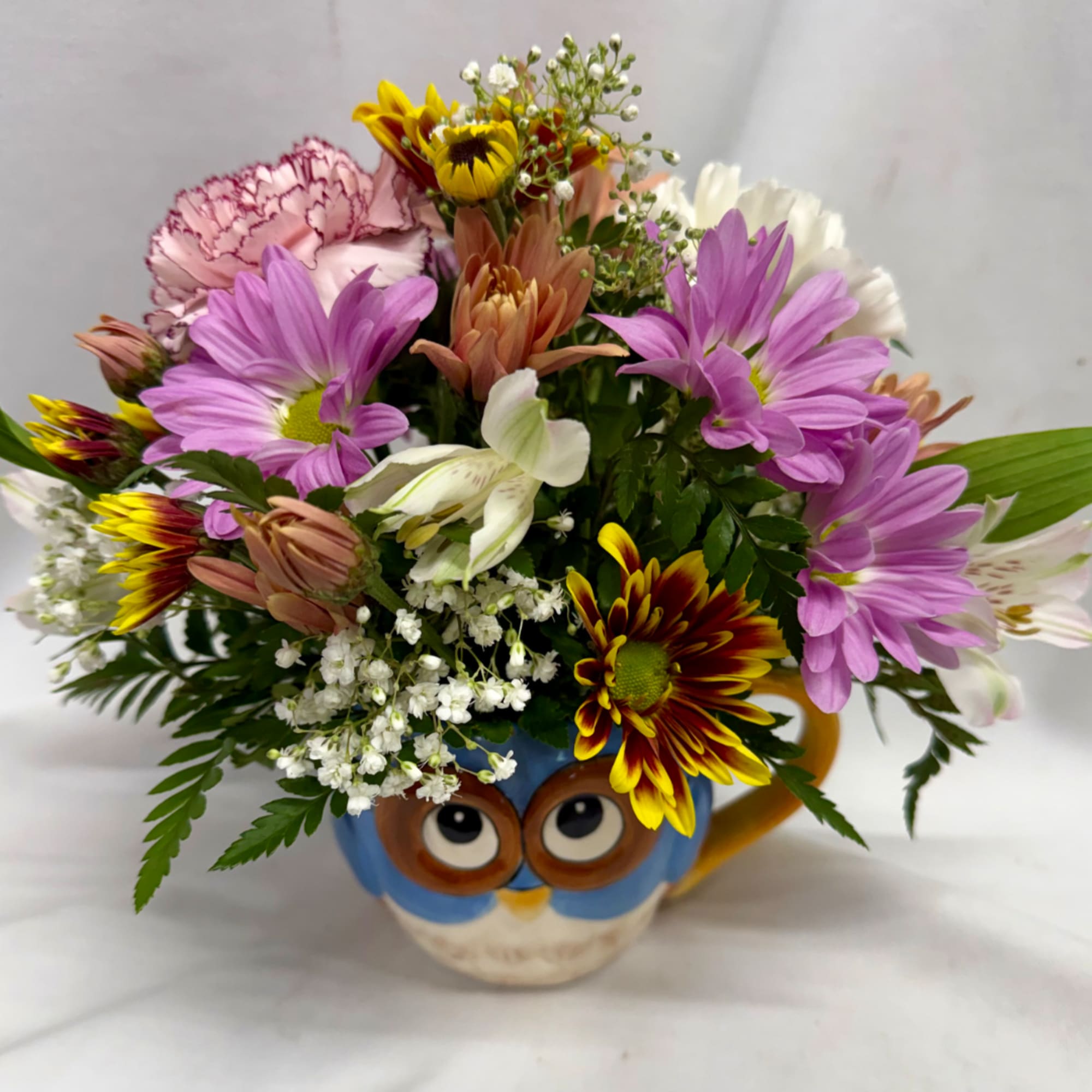 Mixed bouquet in an owl mug with purple, white, pink, and yellow flowers