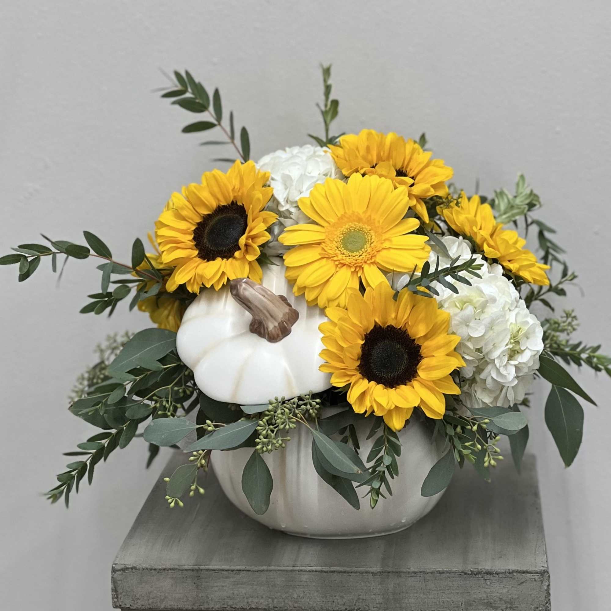 Sunflower and white hydrangea arrangement in a white pumpkin container