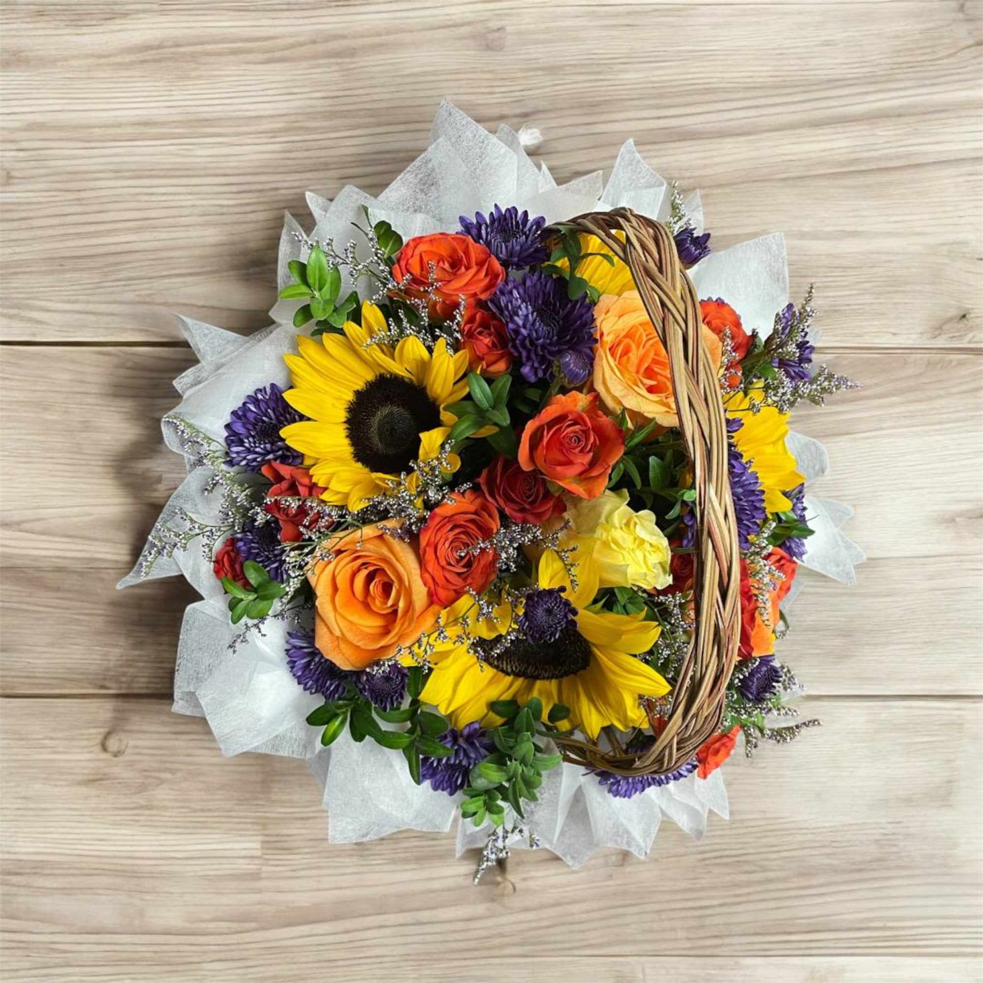 Basket bouquet with sunflowers, orange roses, and purple blooms