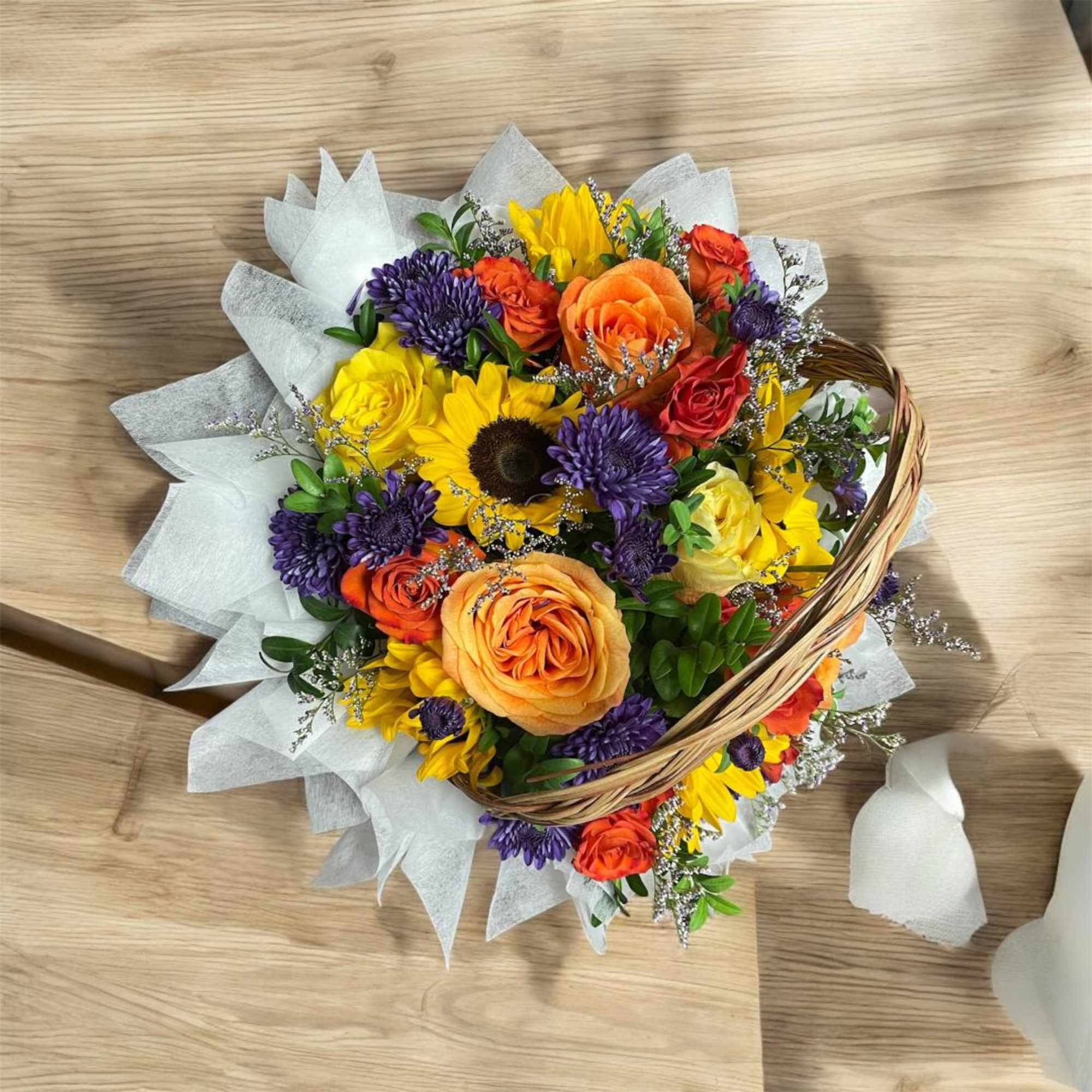 Mixed bouquet of yellow, orange, red, and purple flowers in wrapping