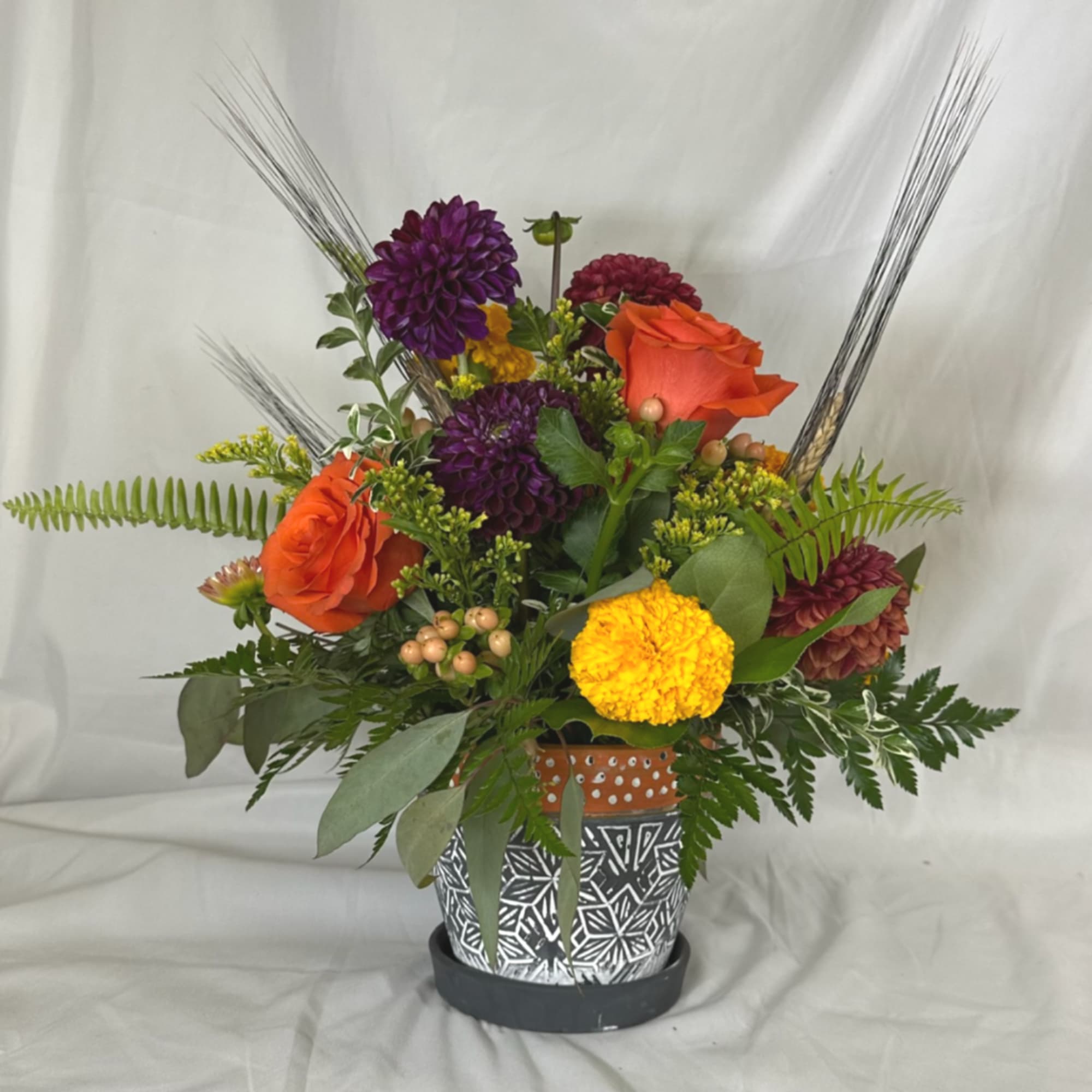 Mixed bouquet in a patterned pot with orange roses and purple mums