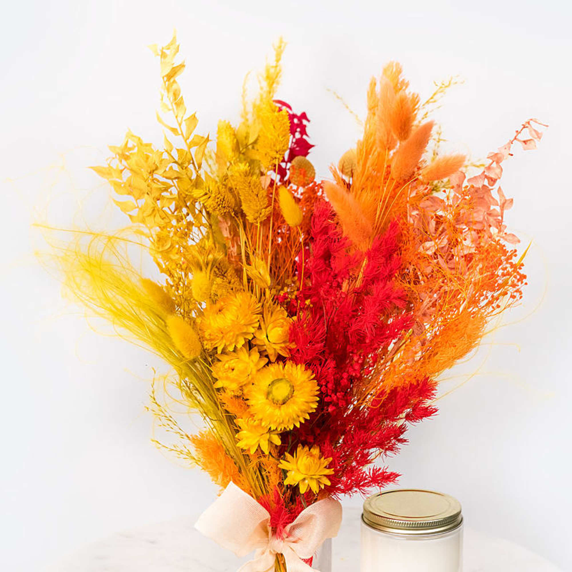 Bright dried flower bouquet in yellow, orange, and red with a ribbon tie