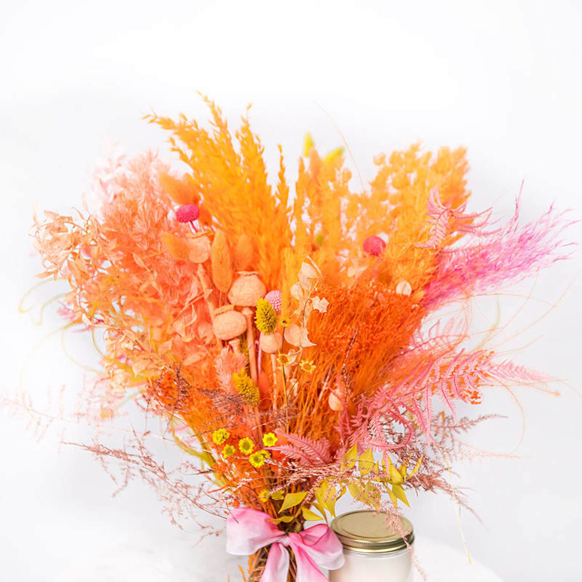 Bright orange and pink dried floral arrangement with a pink ribbon in a jar
