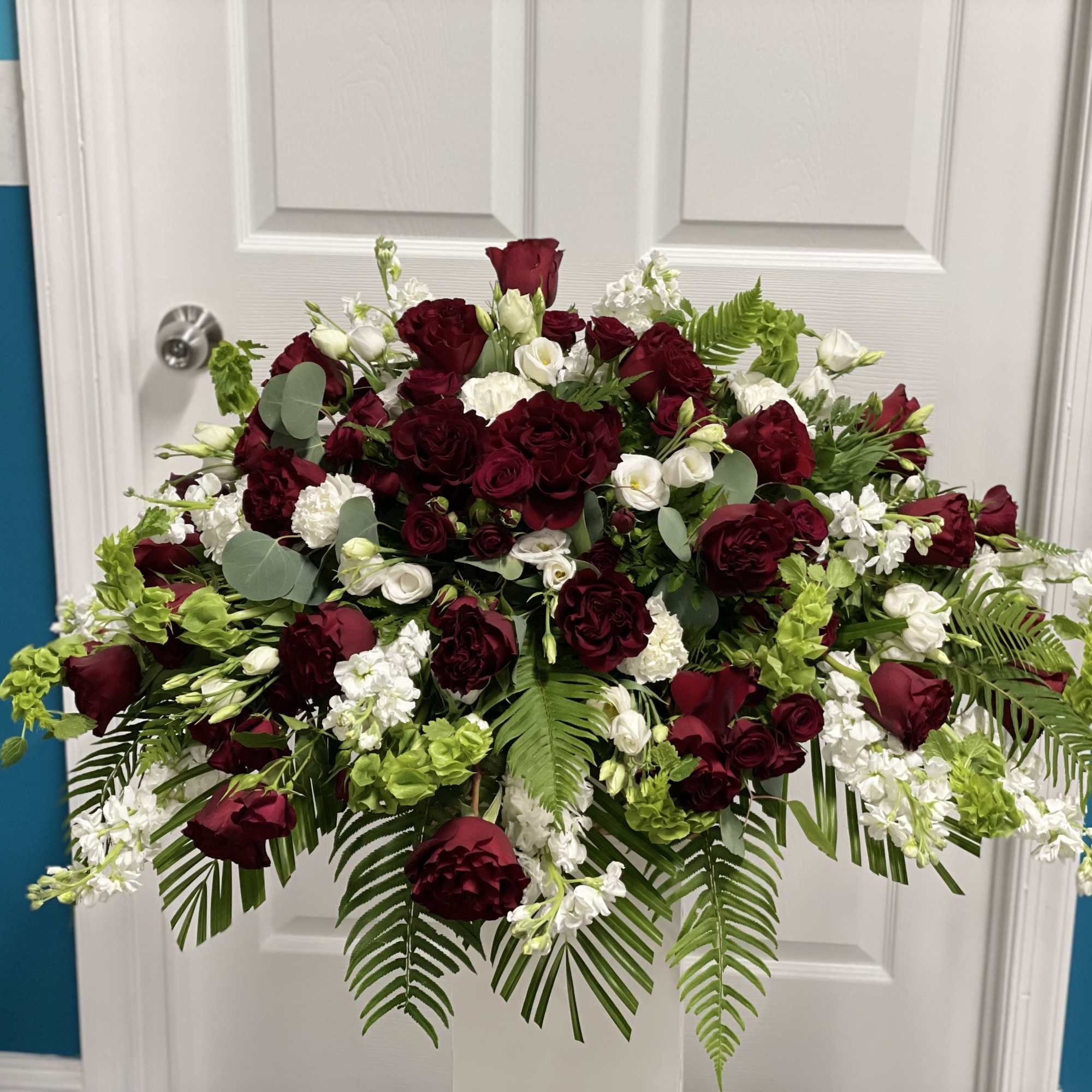 Large arrangement of burgundy and white flowers with fern foliage