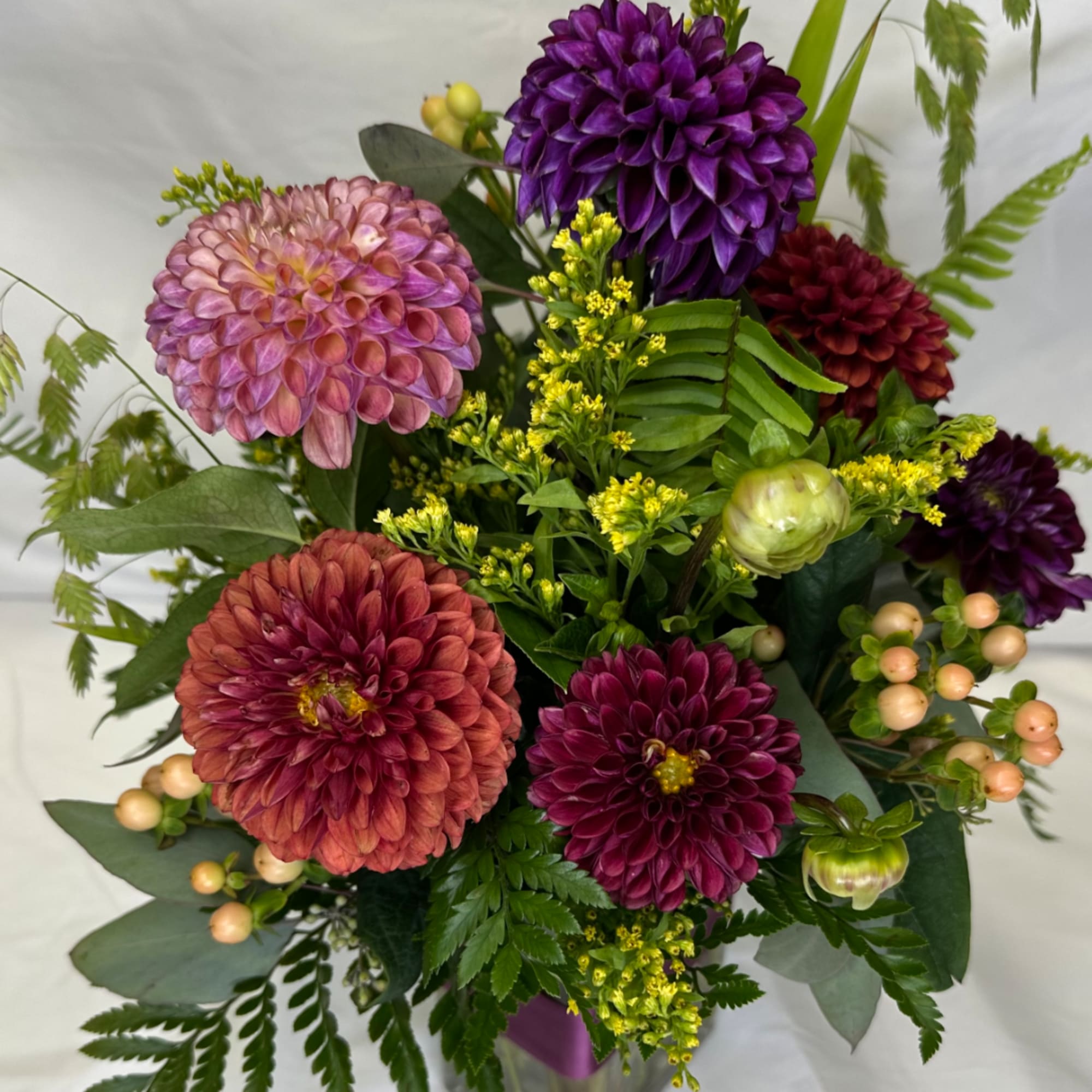 Mixed bouquet of purple, pink, and red dahlias with greenery