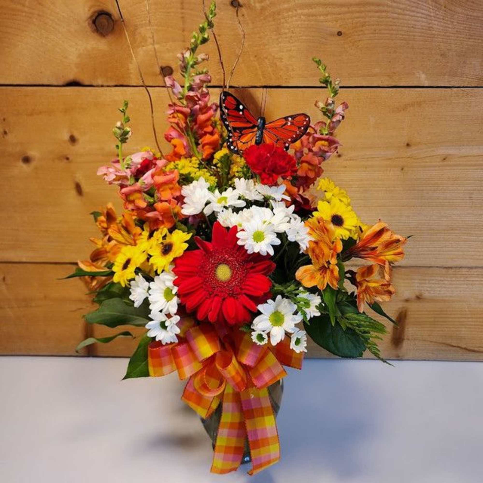 Colorful bouquet with daisies and a butterfly decoration in a vase