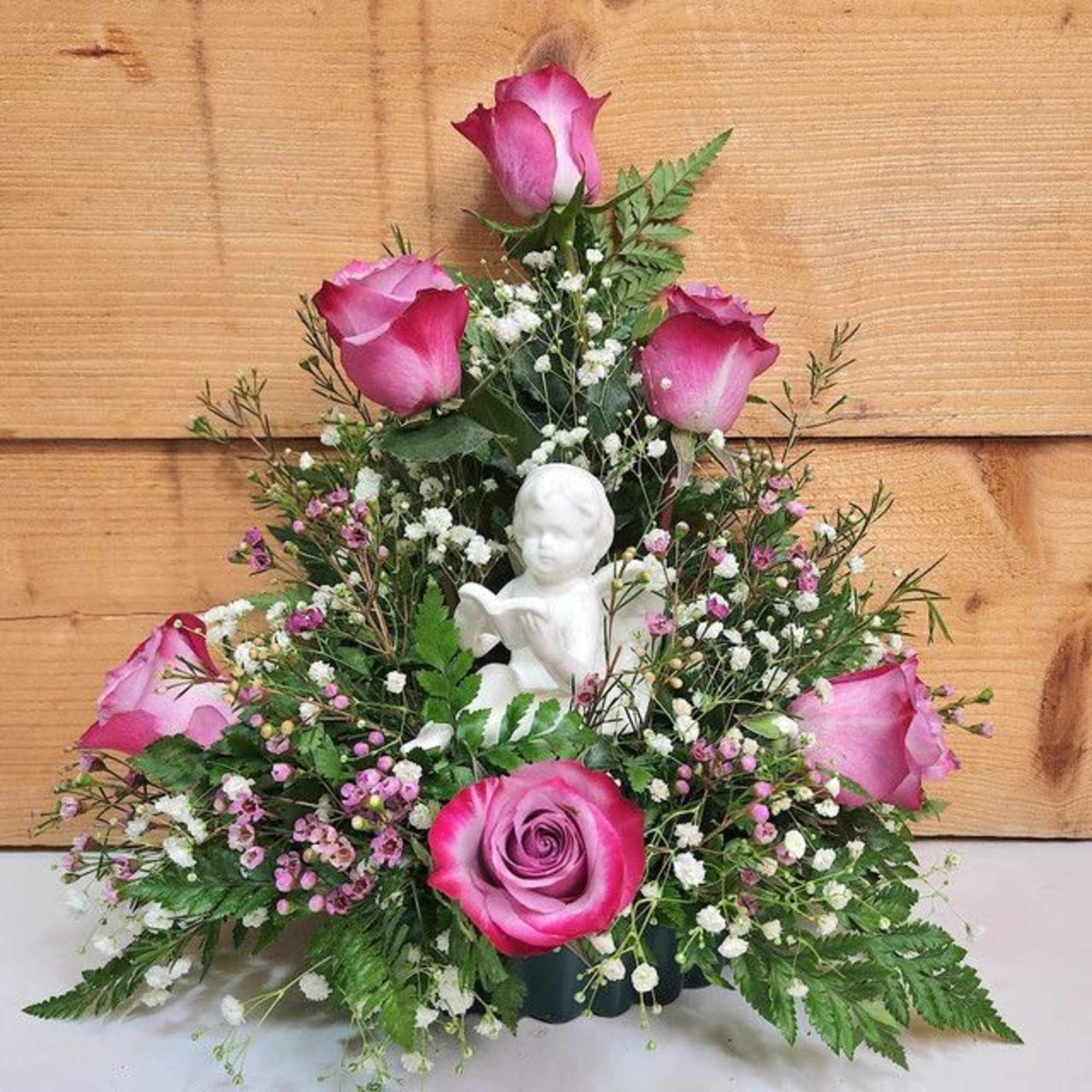 Pink roses arranged around a small white angel figurine