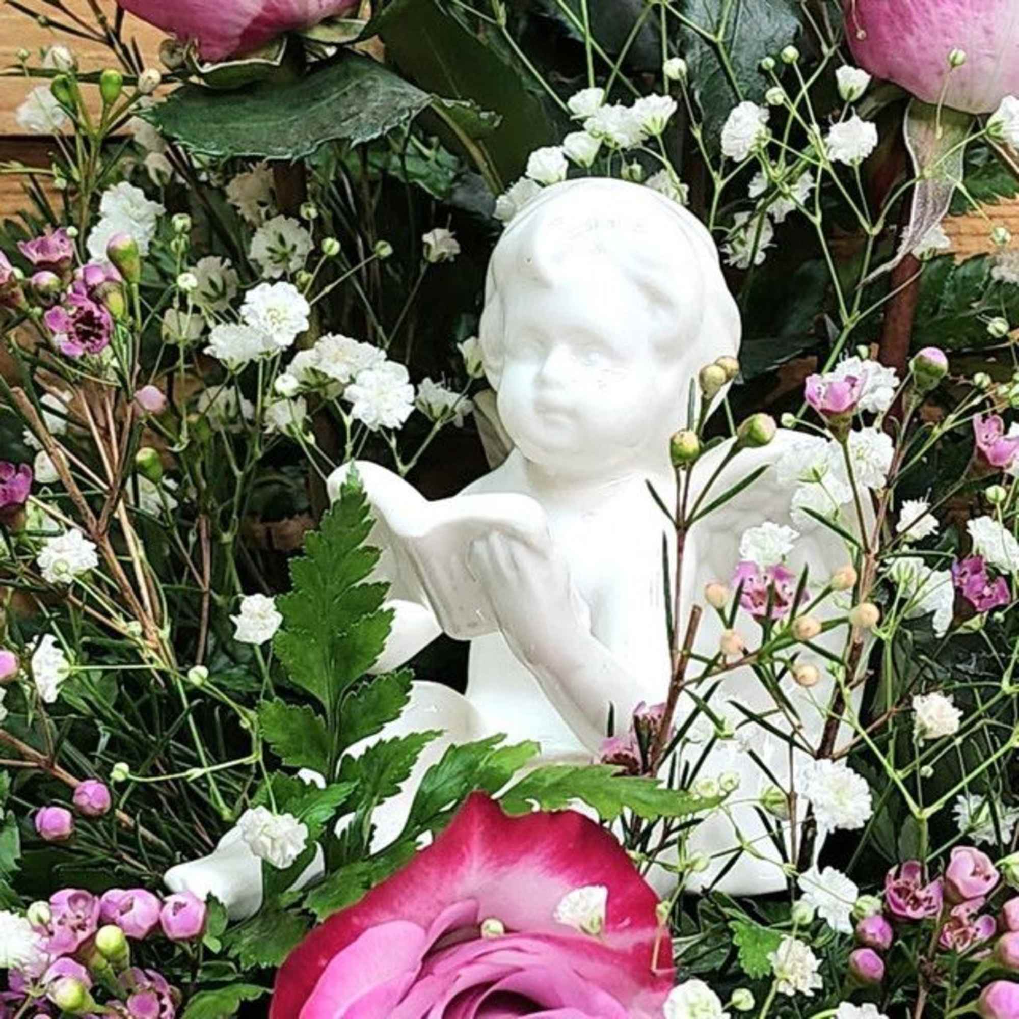 White angel figurine surrounded by pink and white flowers