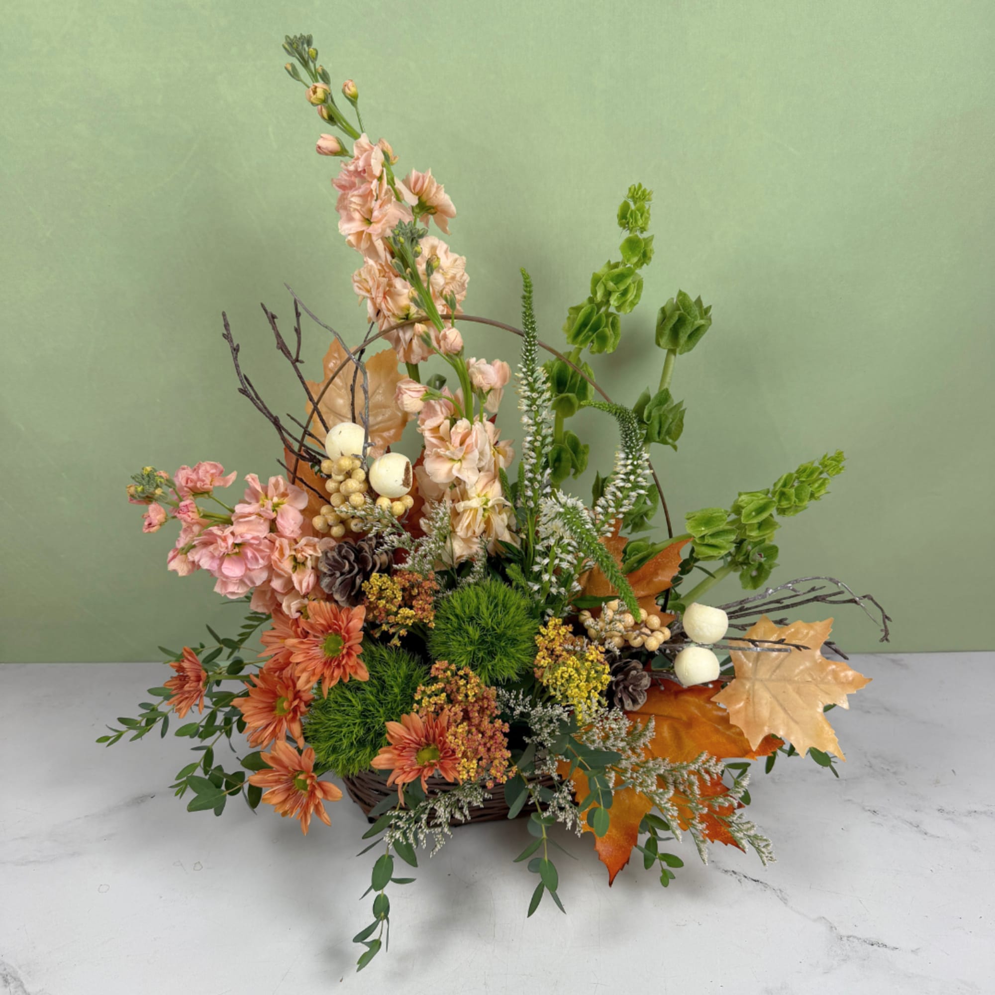 Autumn floral arrangement in a basket with orange and pink blooms