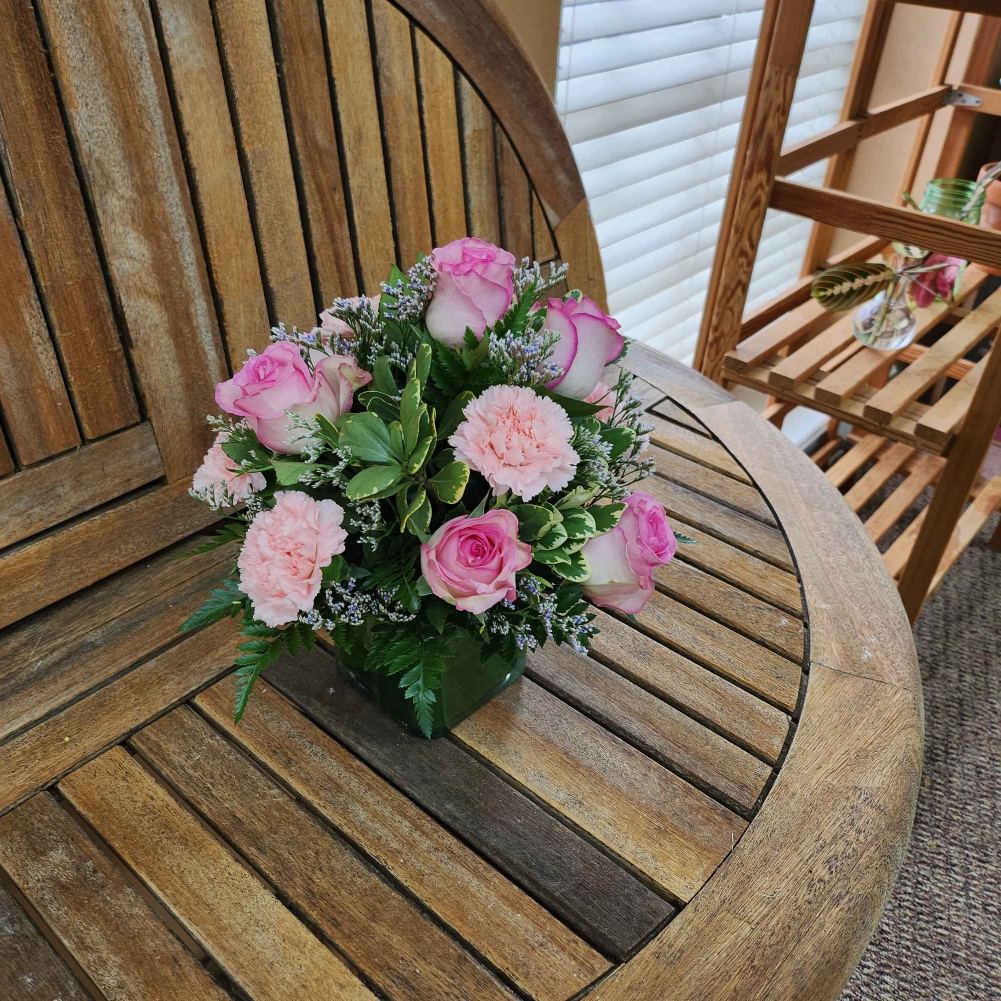 Pink roses and carnations arranged in a small square vase