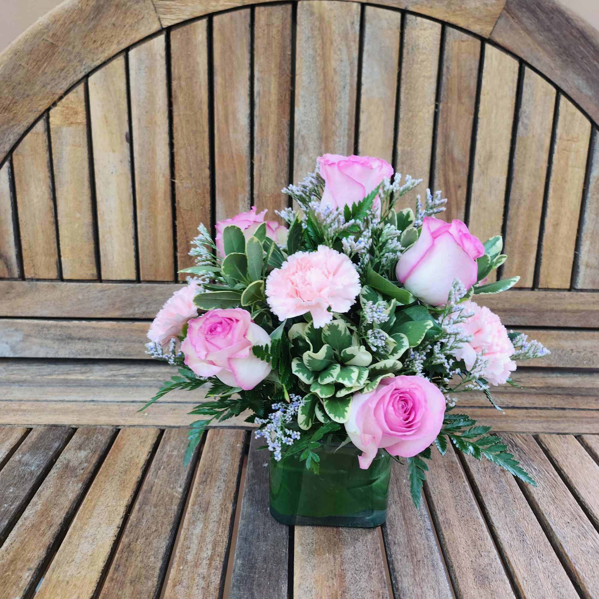 Pink roses and carnations arranged in a square glass vase