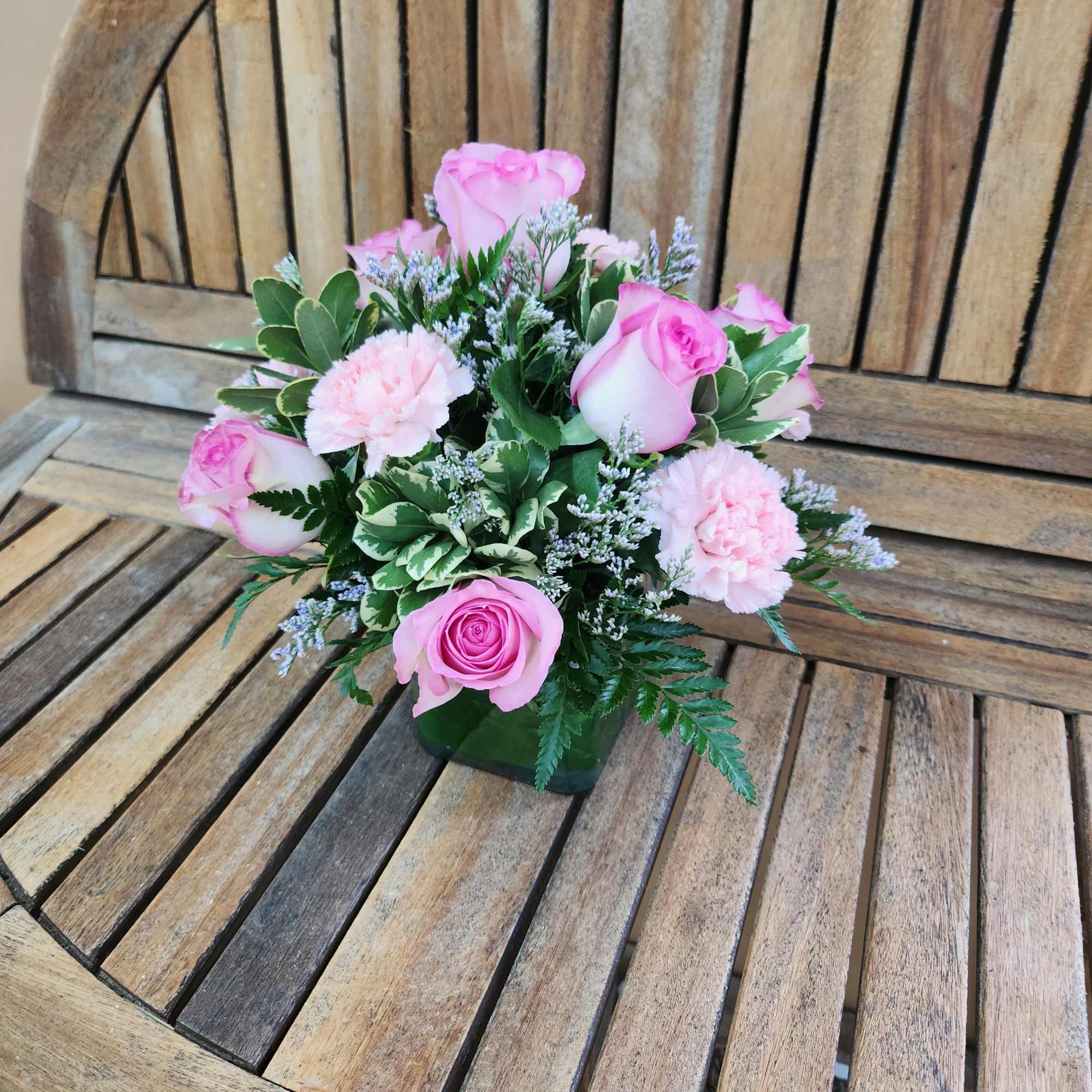Pink roses and carnations arranged in a low square vase