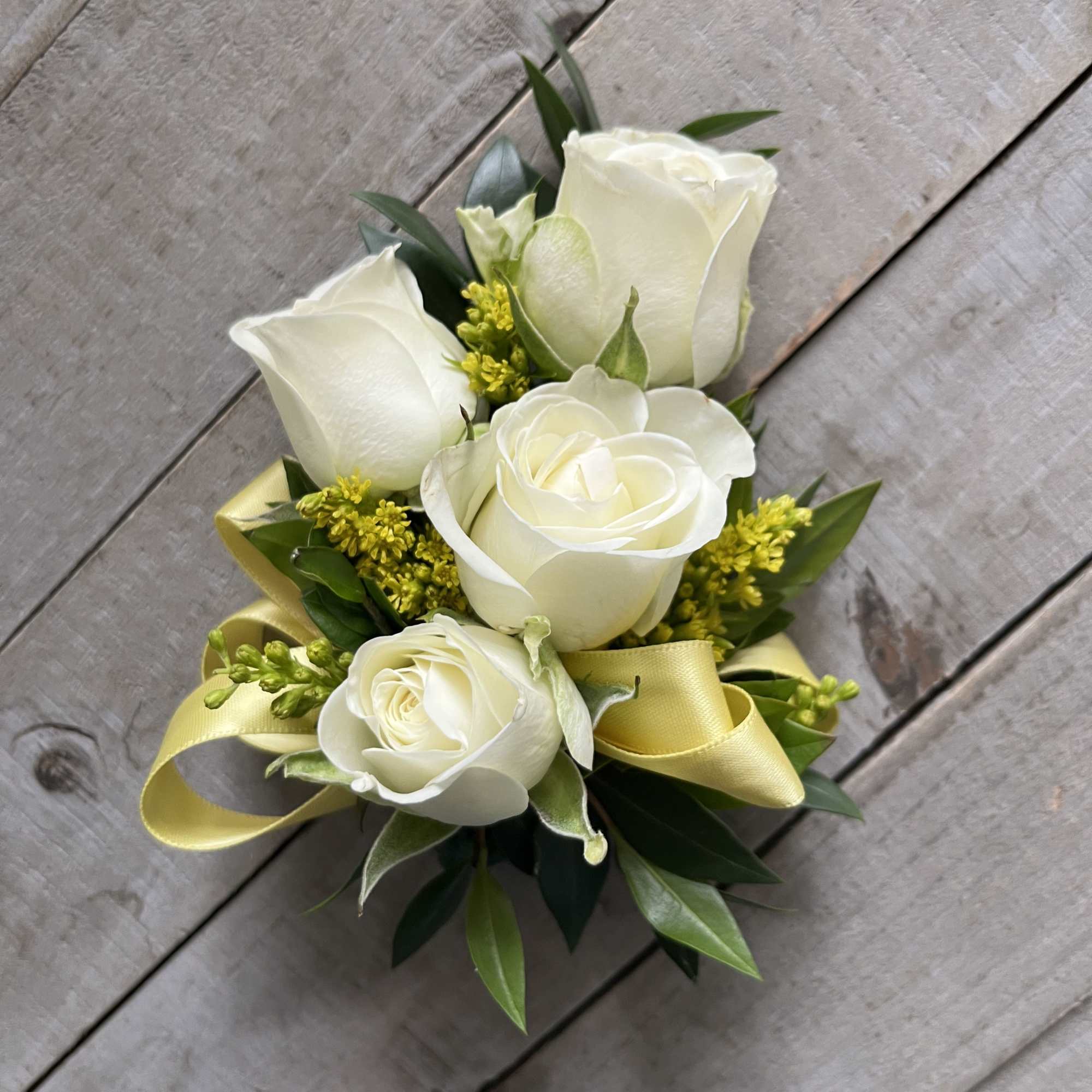 White rose bouquet with yellow ribbon on a wooden surface
