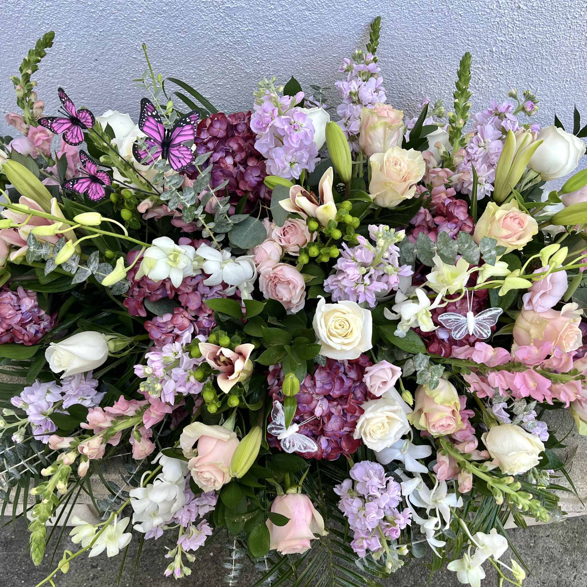 Large pastel floral arrangement with roses, lilies, and purple blooms