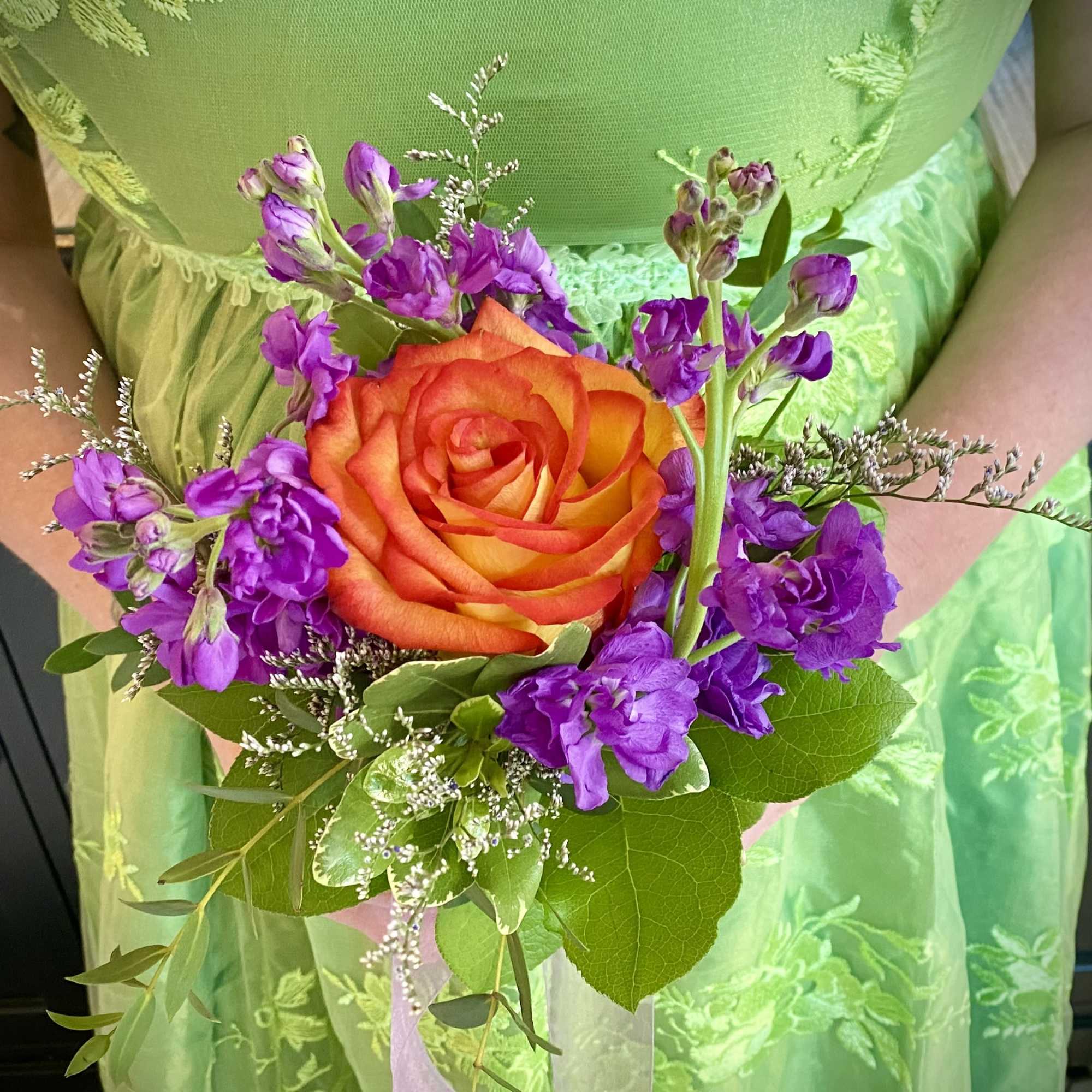 Handheld bouquet with an orange rose and purple flowers