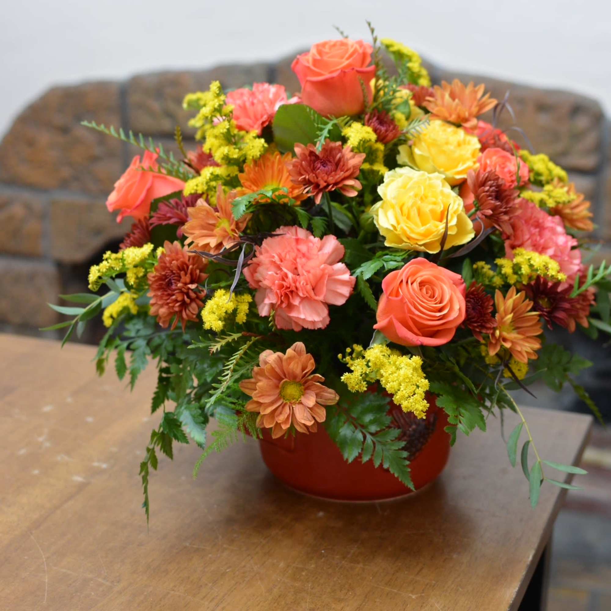 Pinecone harvest glow features a rich blend of fall toned roses, carnations