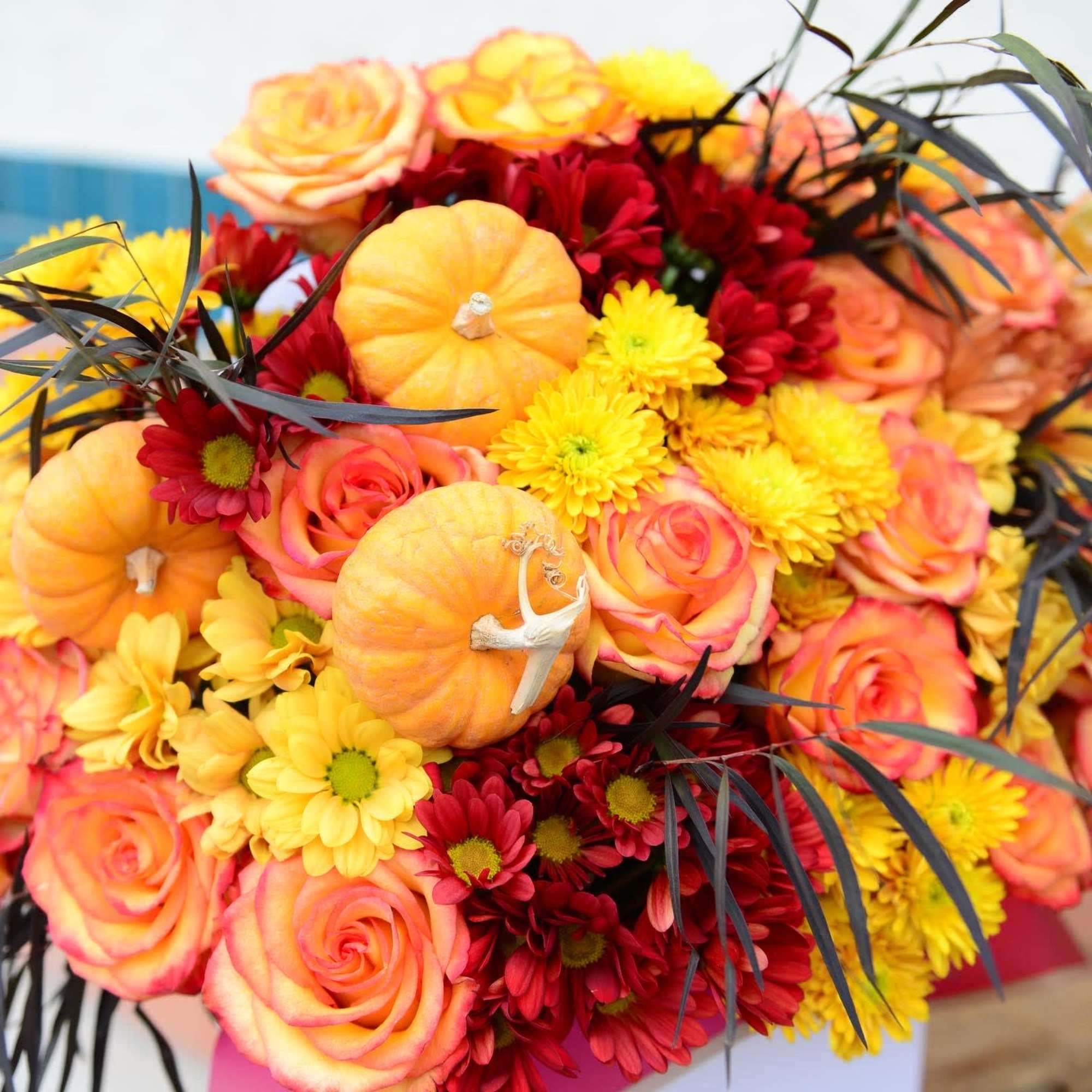 Bouquet of orange roses, yellow daisies, and small pumpkins