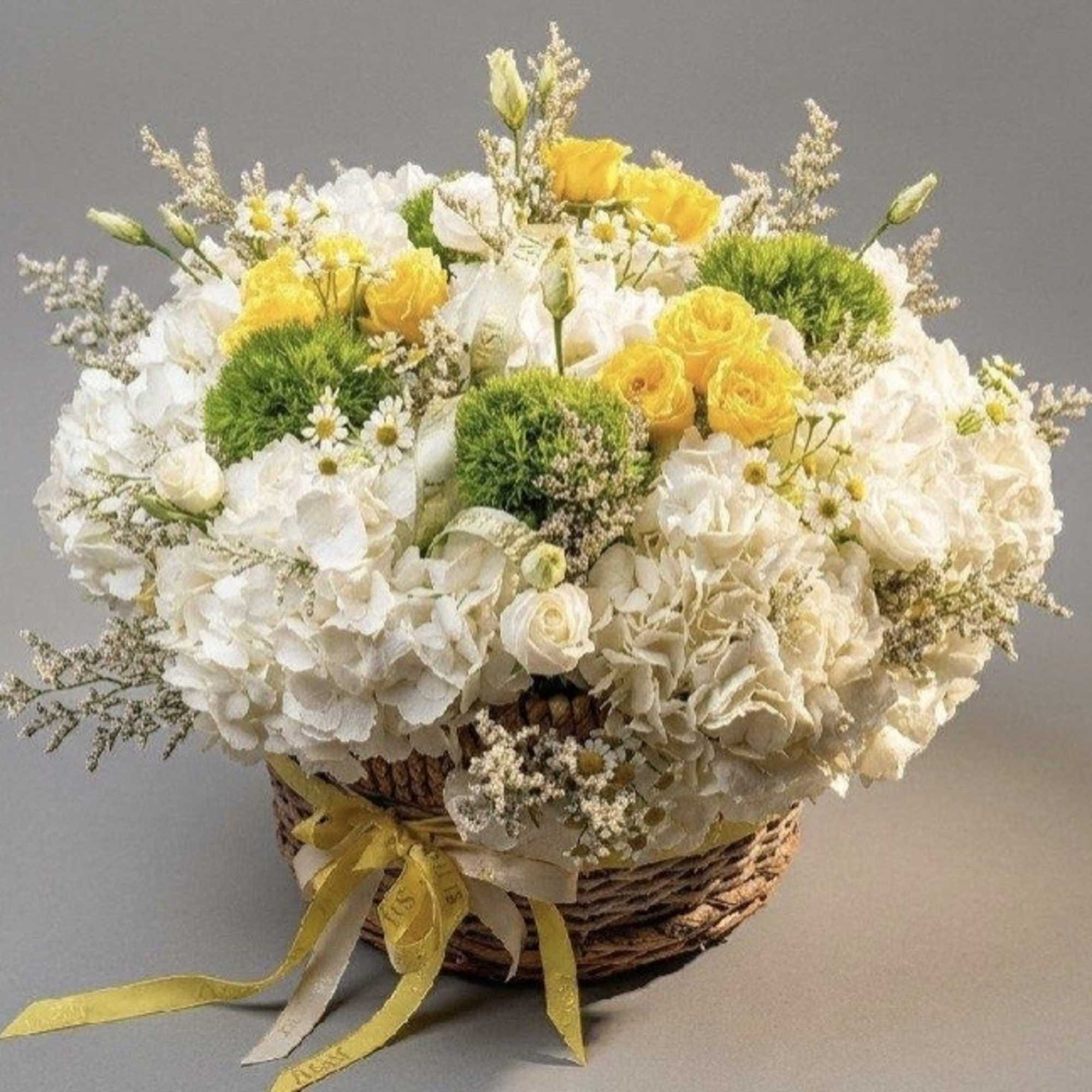 White and yellow flower arrangement in a wicker basket