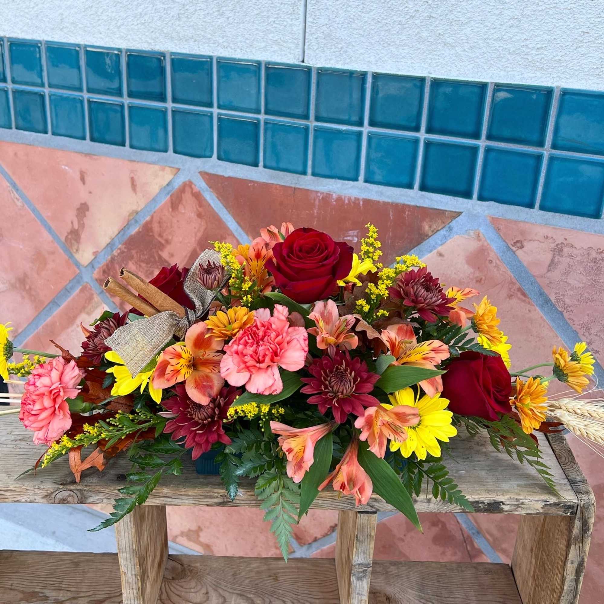 Mixed bouquet of roses, carnations, and daisies on a wooden bench