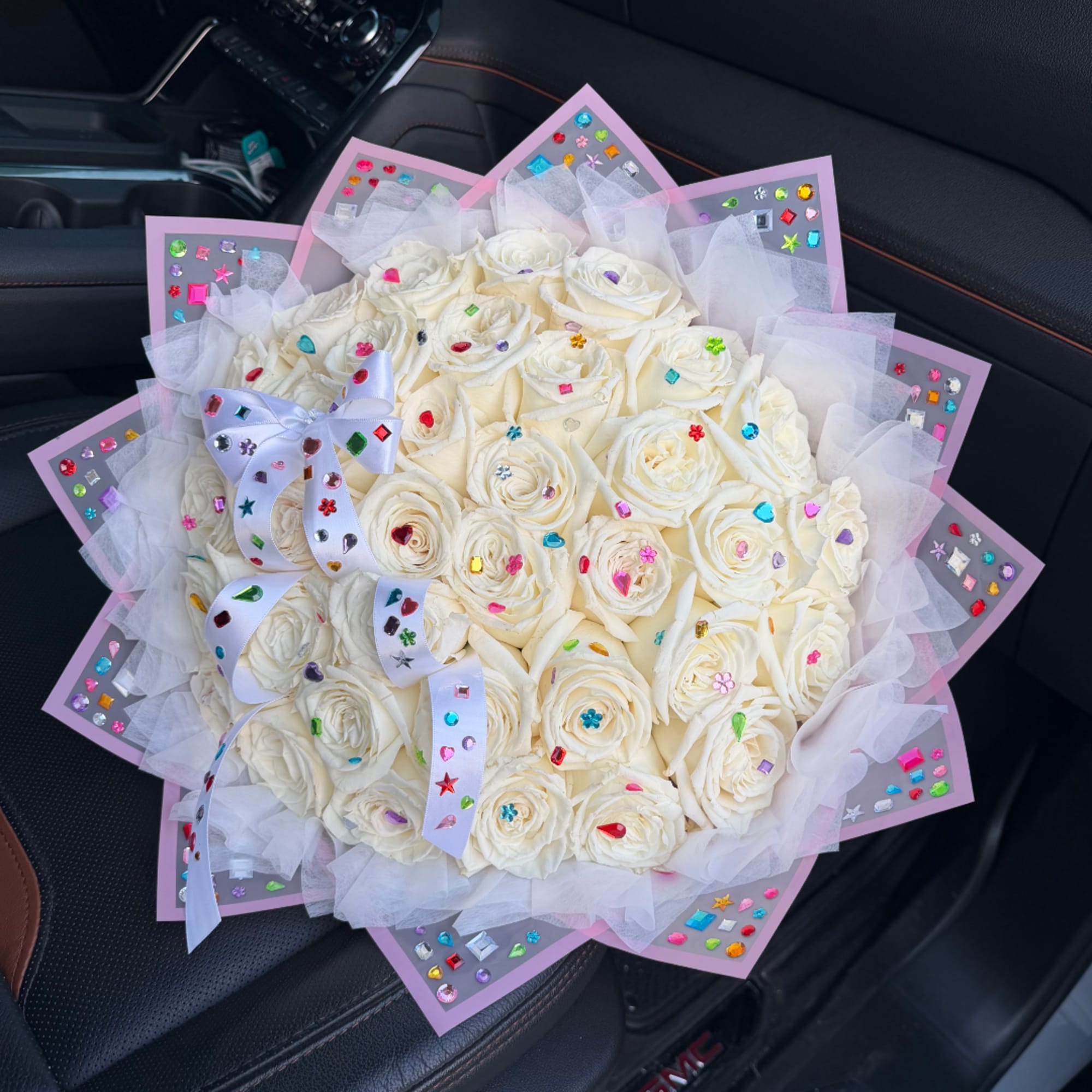 Bouquet of white roses wrapped in pink paper with a white ribbon