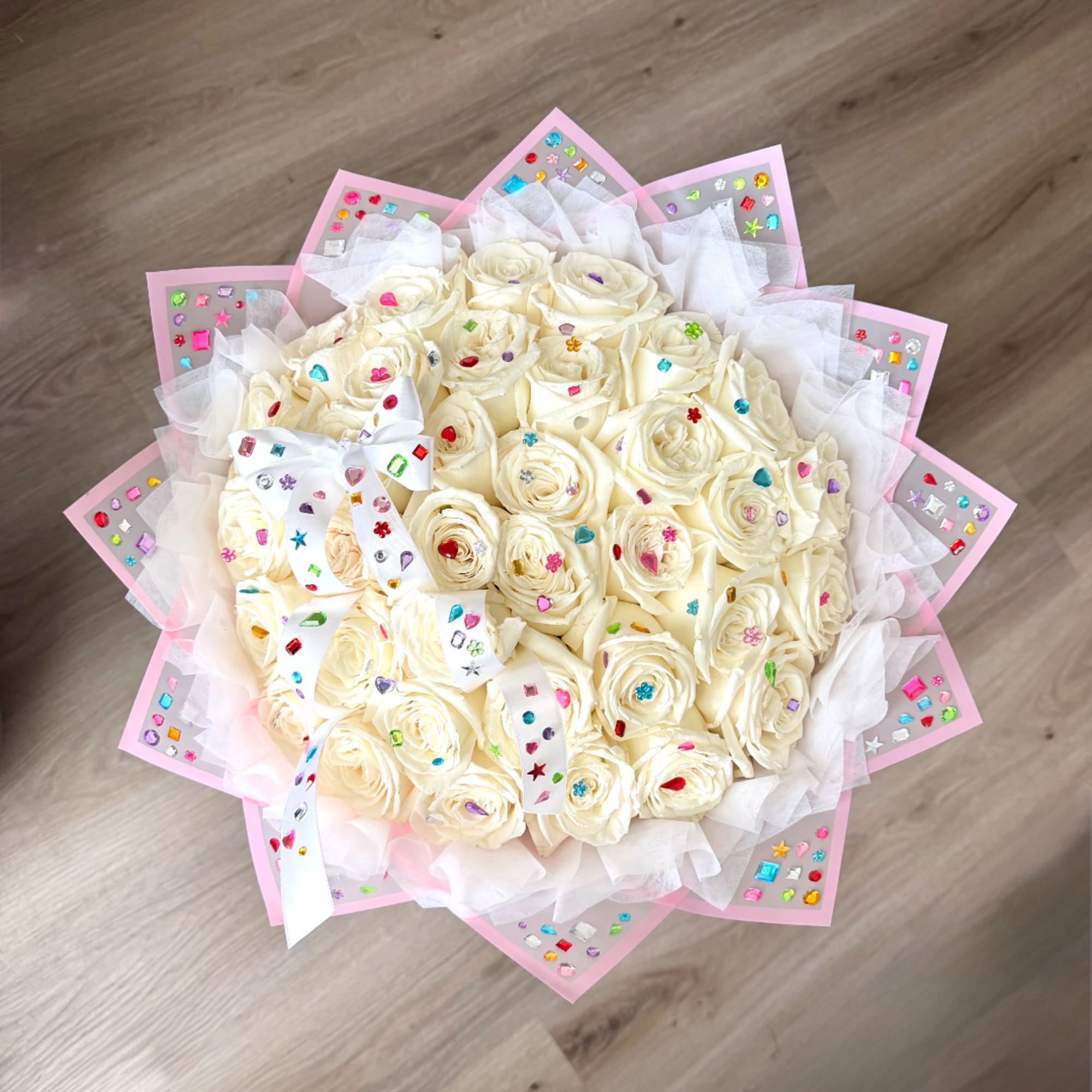Bouquet of cream roses wrapped in pink paper with white ribbon