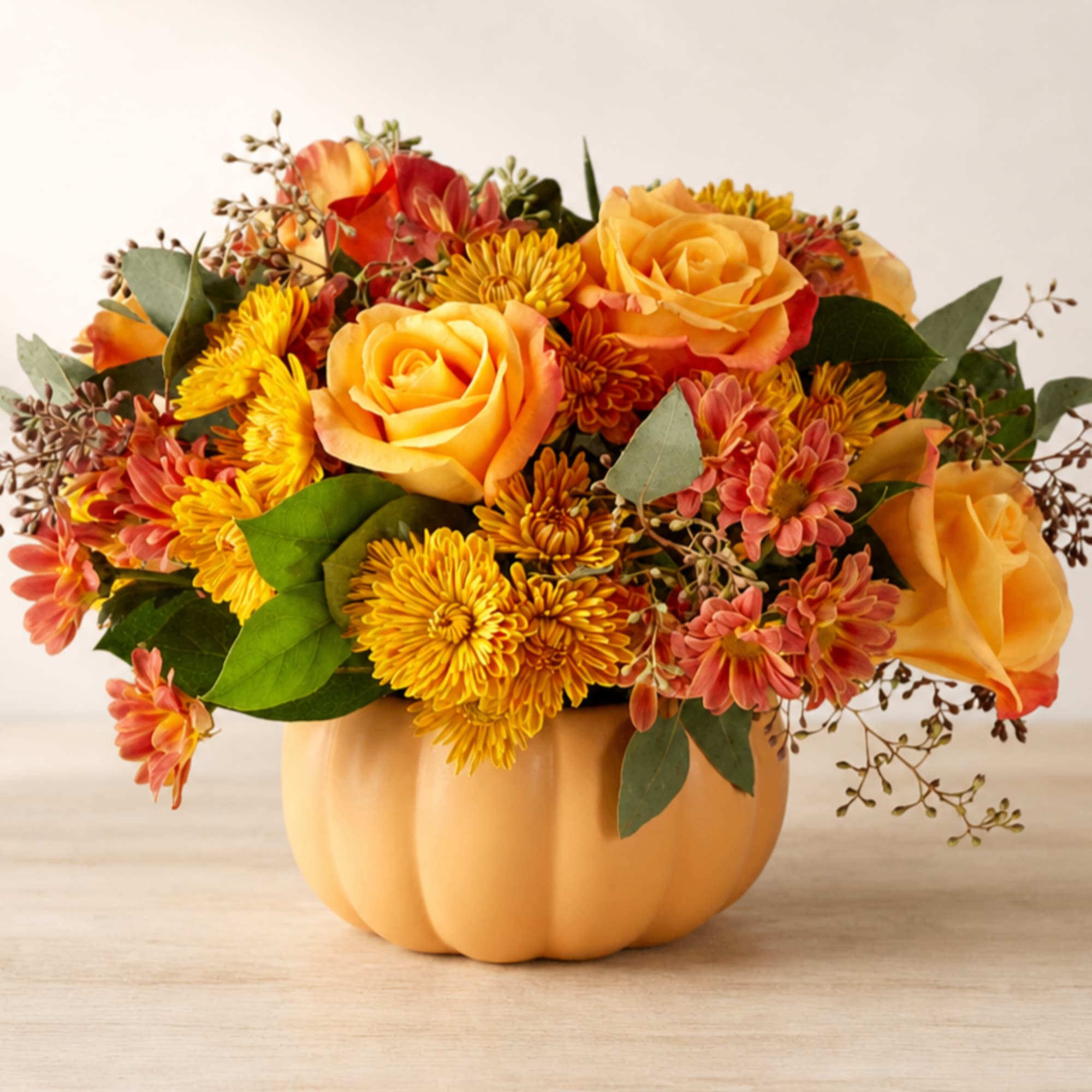 Orange and yellow flower arrangement in a pumpkin-shaped container