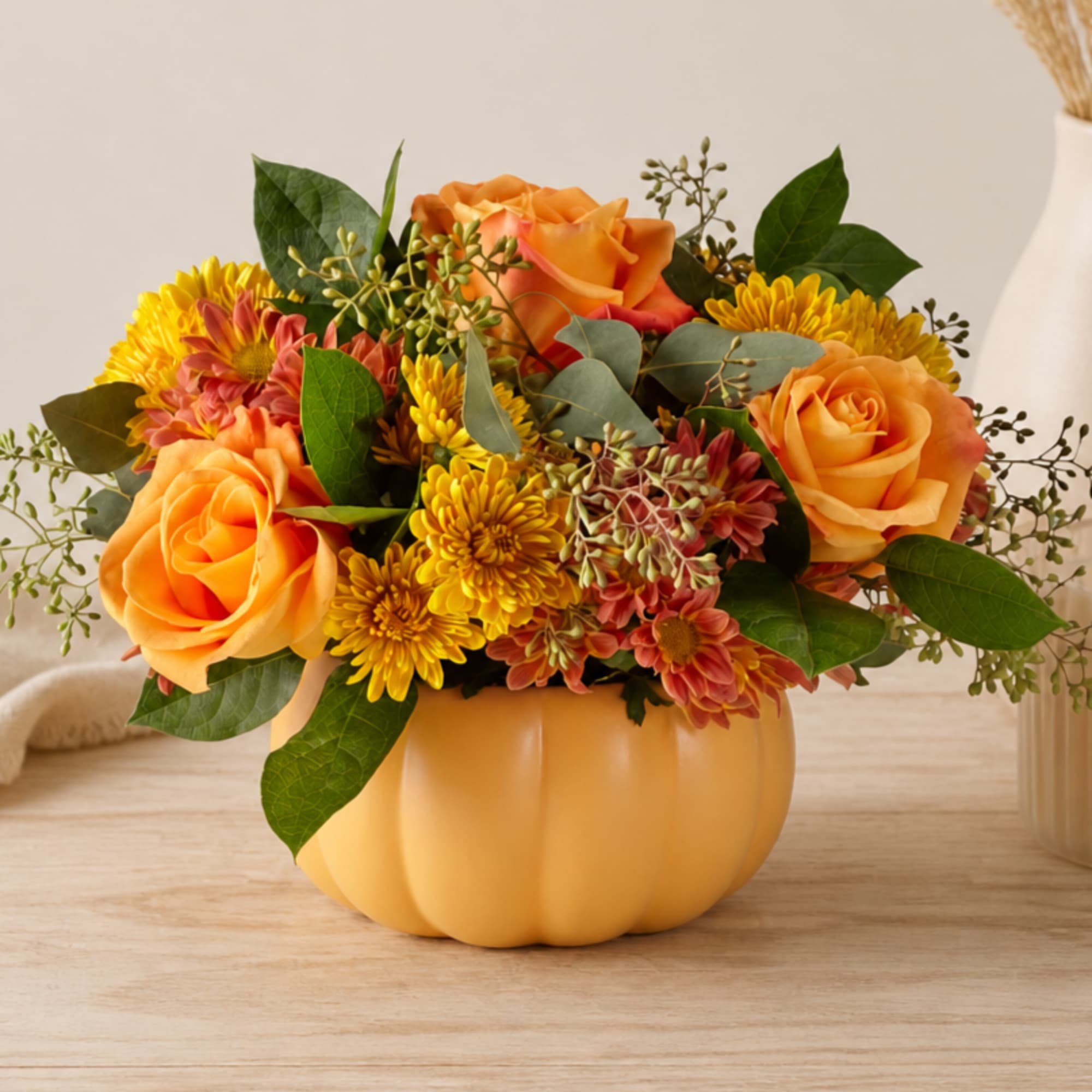 Orange roses and yellow mums arranged in a pumpkin-shaped vase