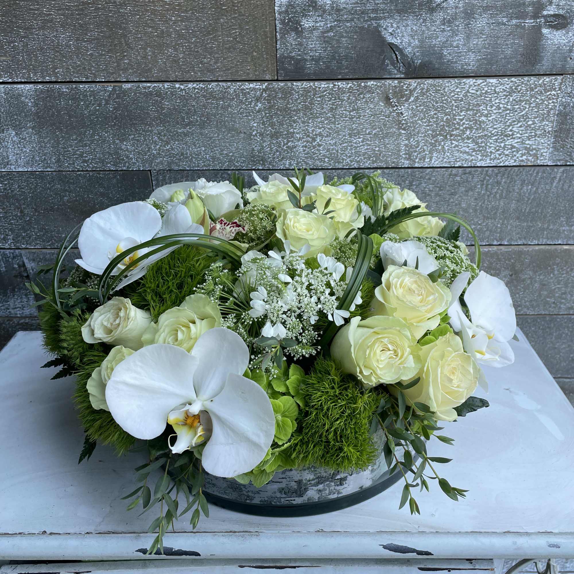White orchids and pale roses in a low round arrangement