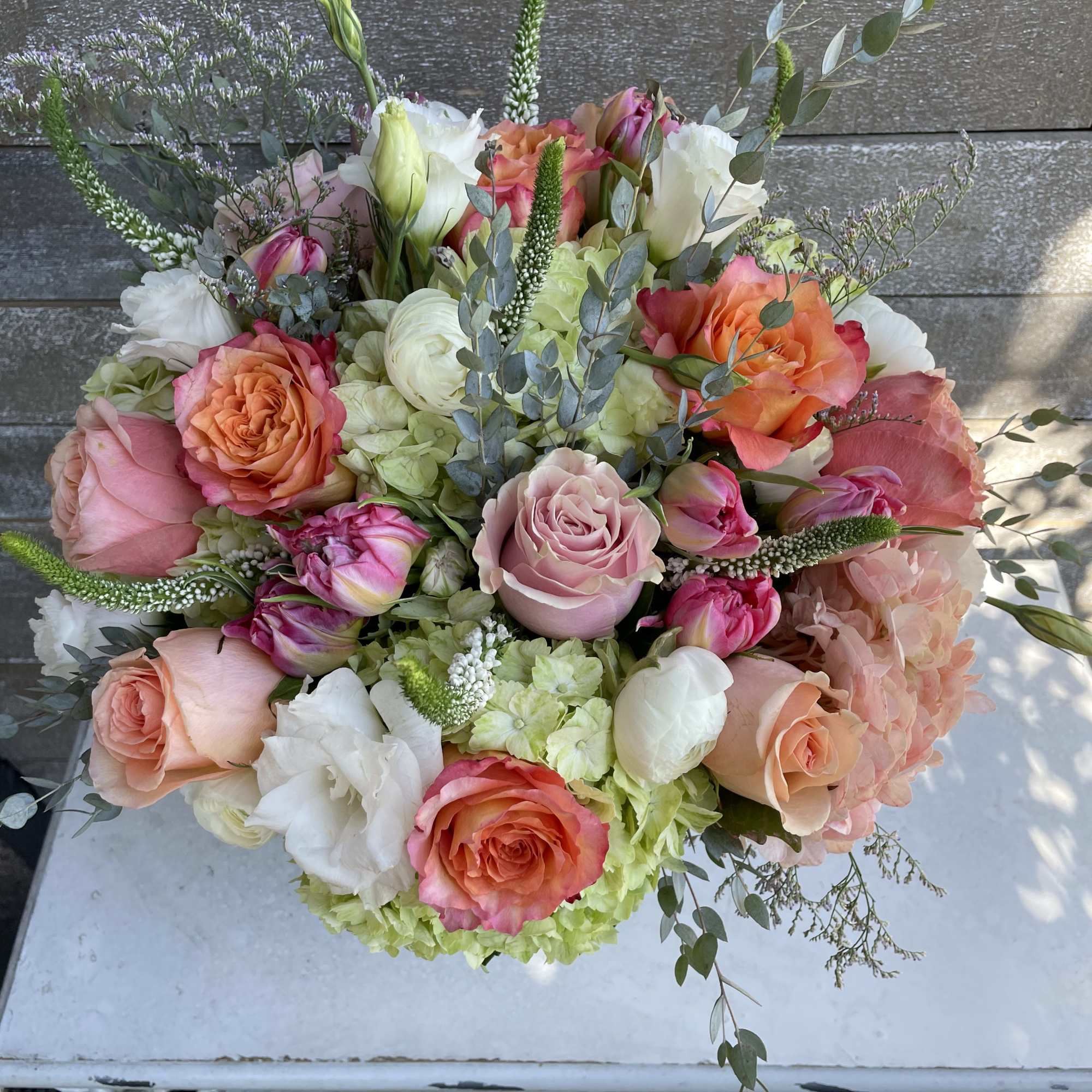 Bouquet of pink and peach roses with white blooms and greenery