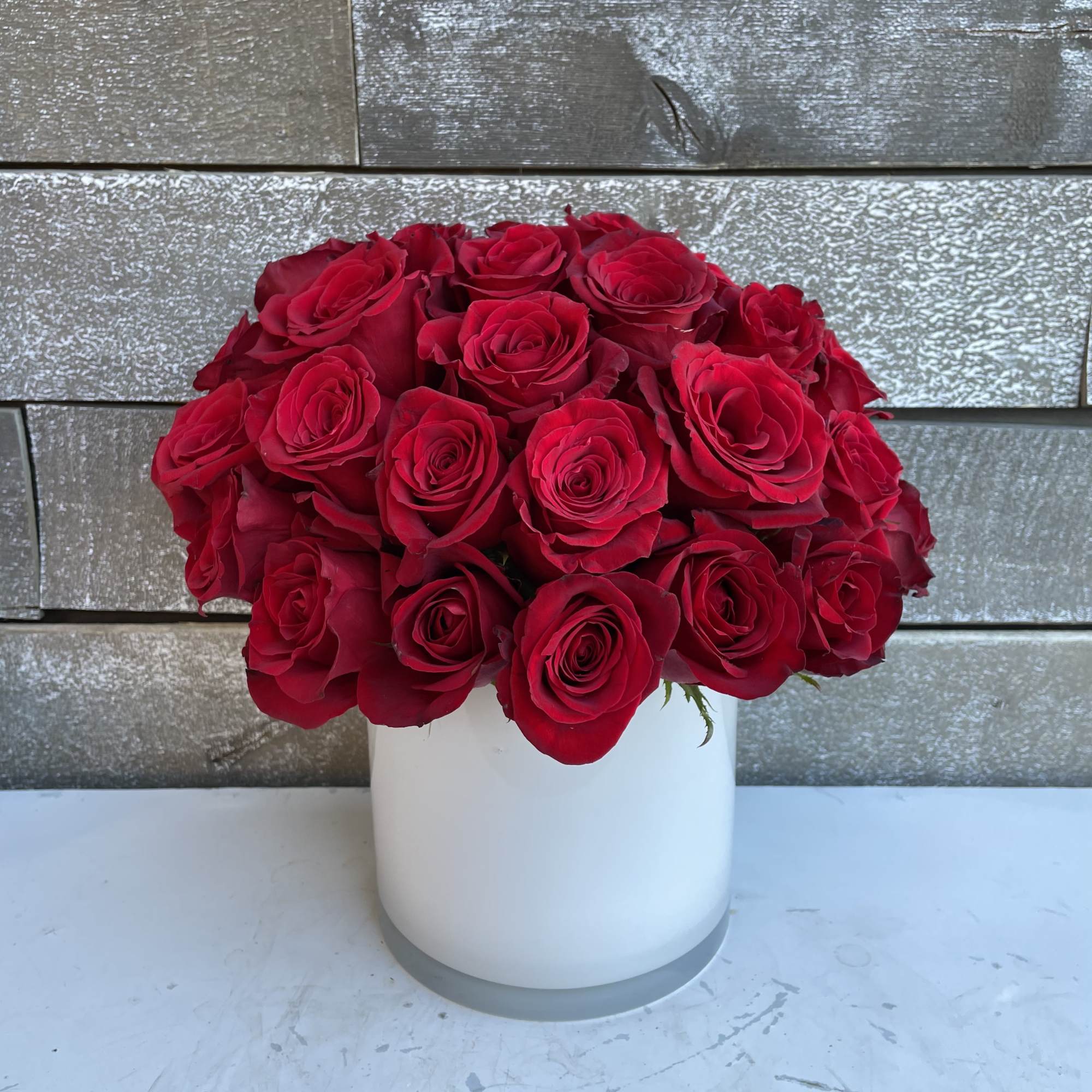 Red roses arranged in a white cylindrical vase