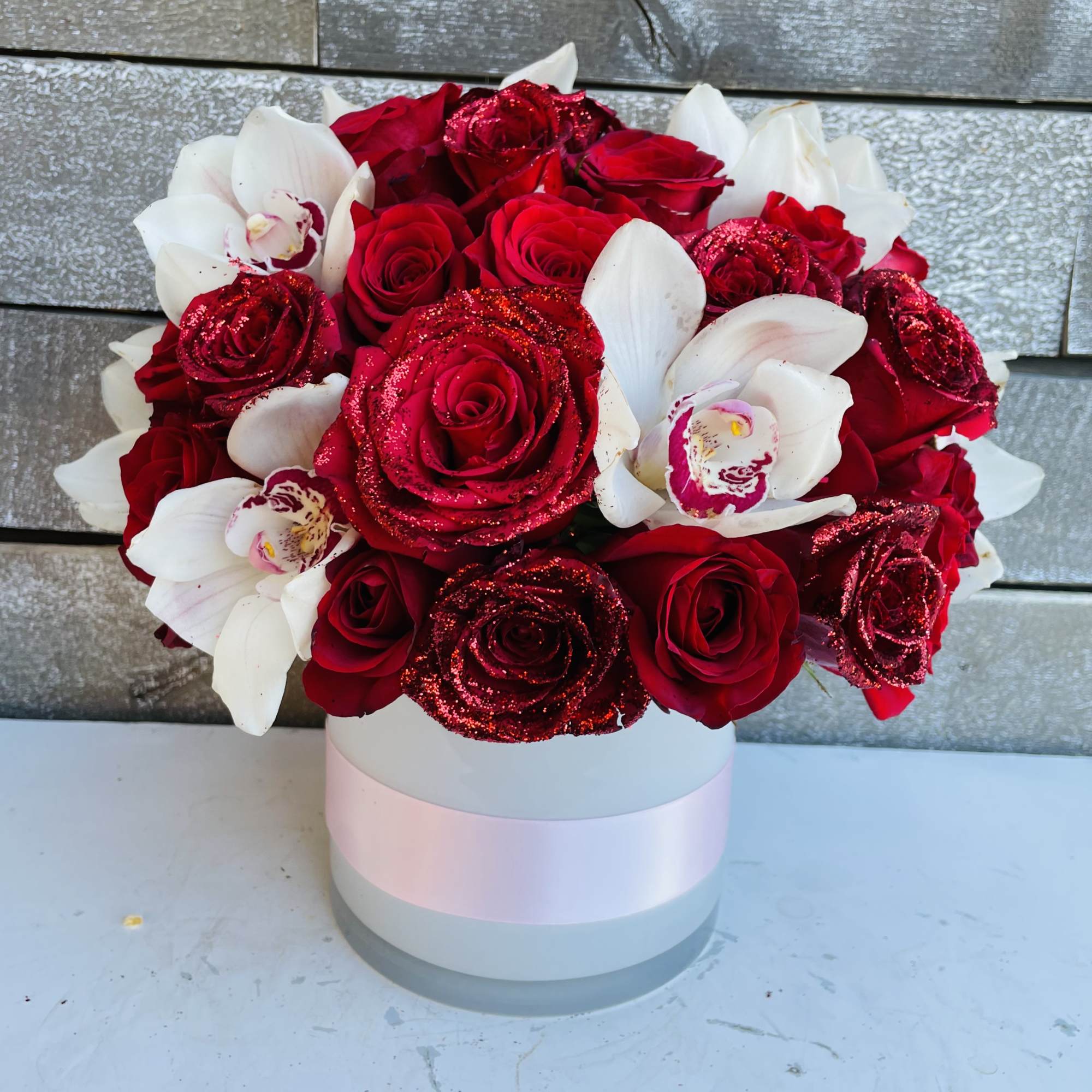 Red roses and white orchids in a round hat box