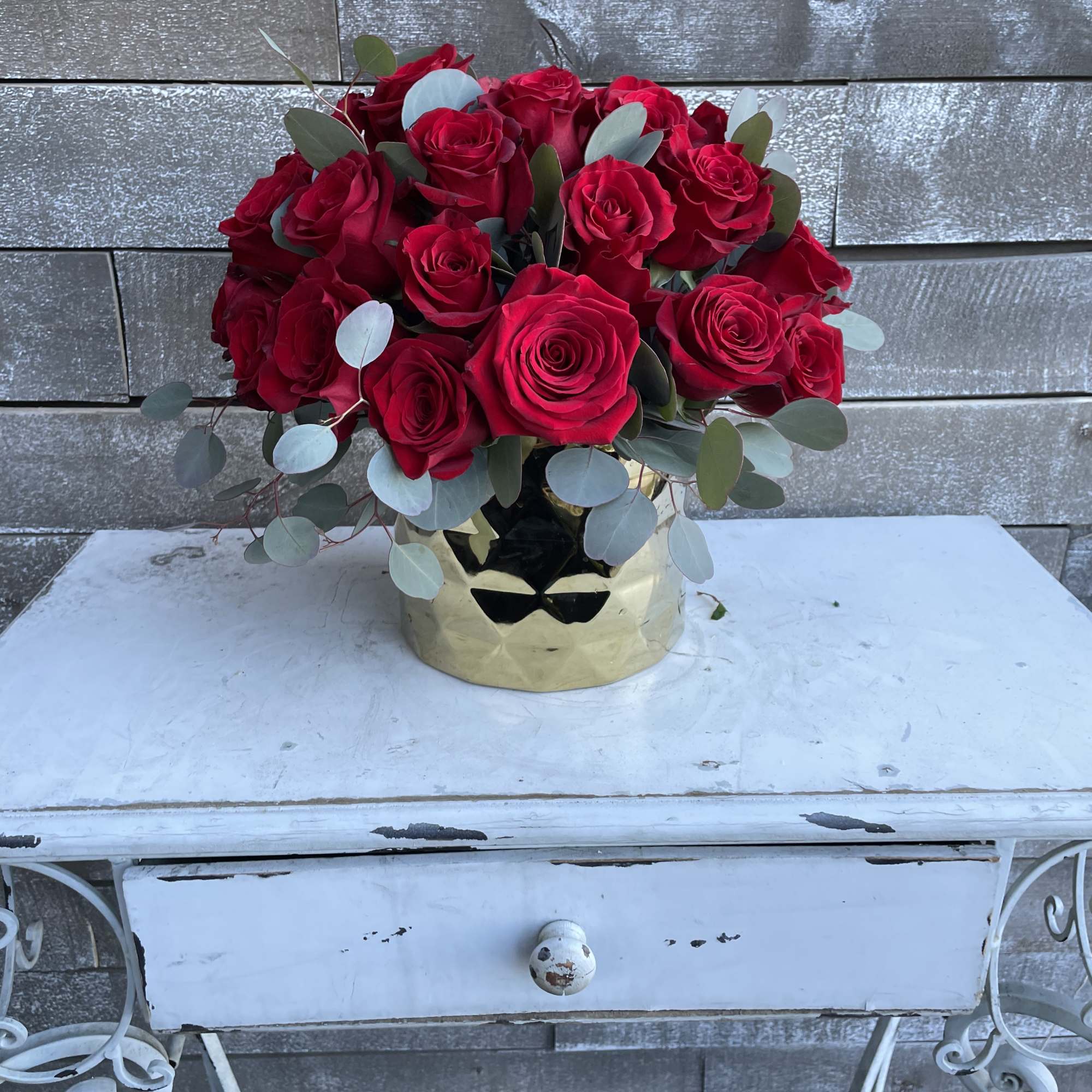 Bouquet of red roses in a gold vase with eucalyptus