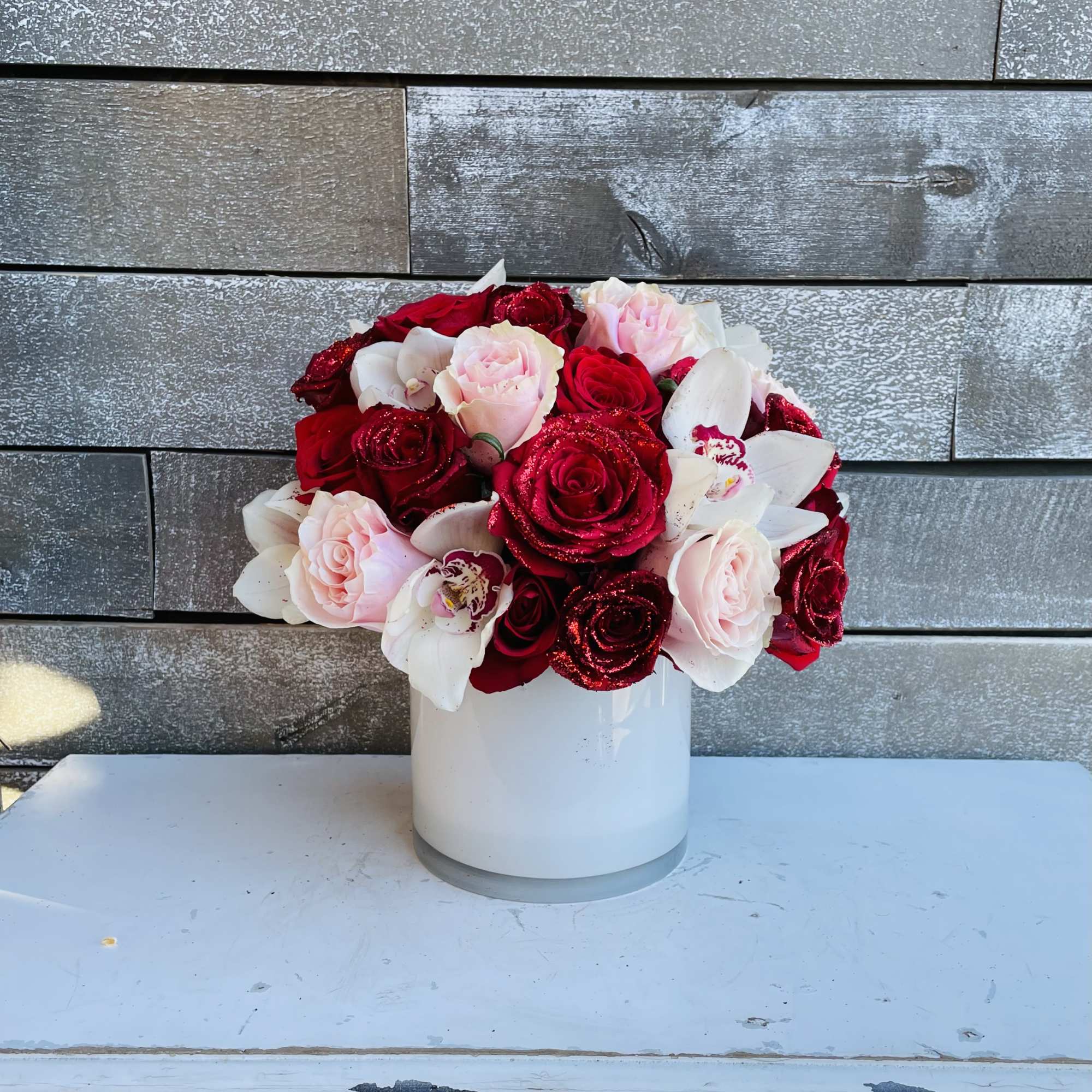 Red and pale pink roses arranged in a white vase