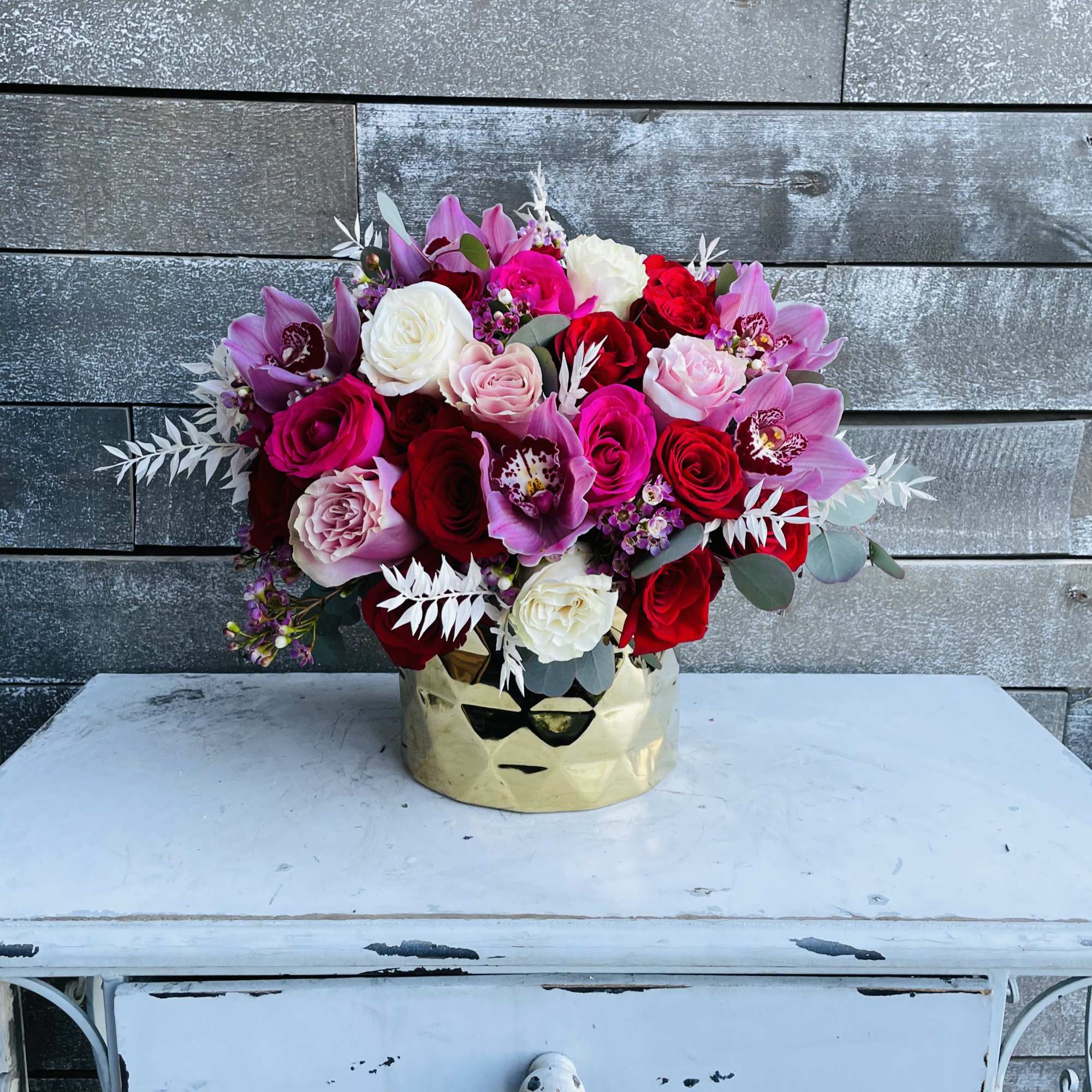 Bouquet of pink, red, and white roses in a gold vase
