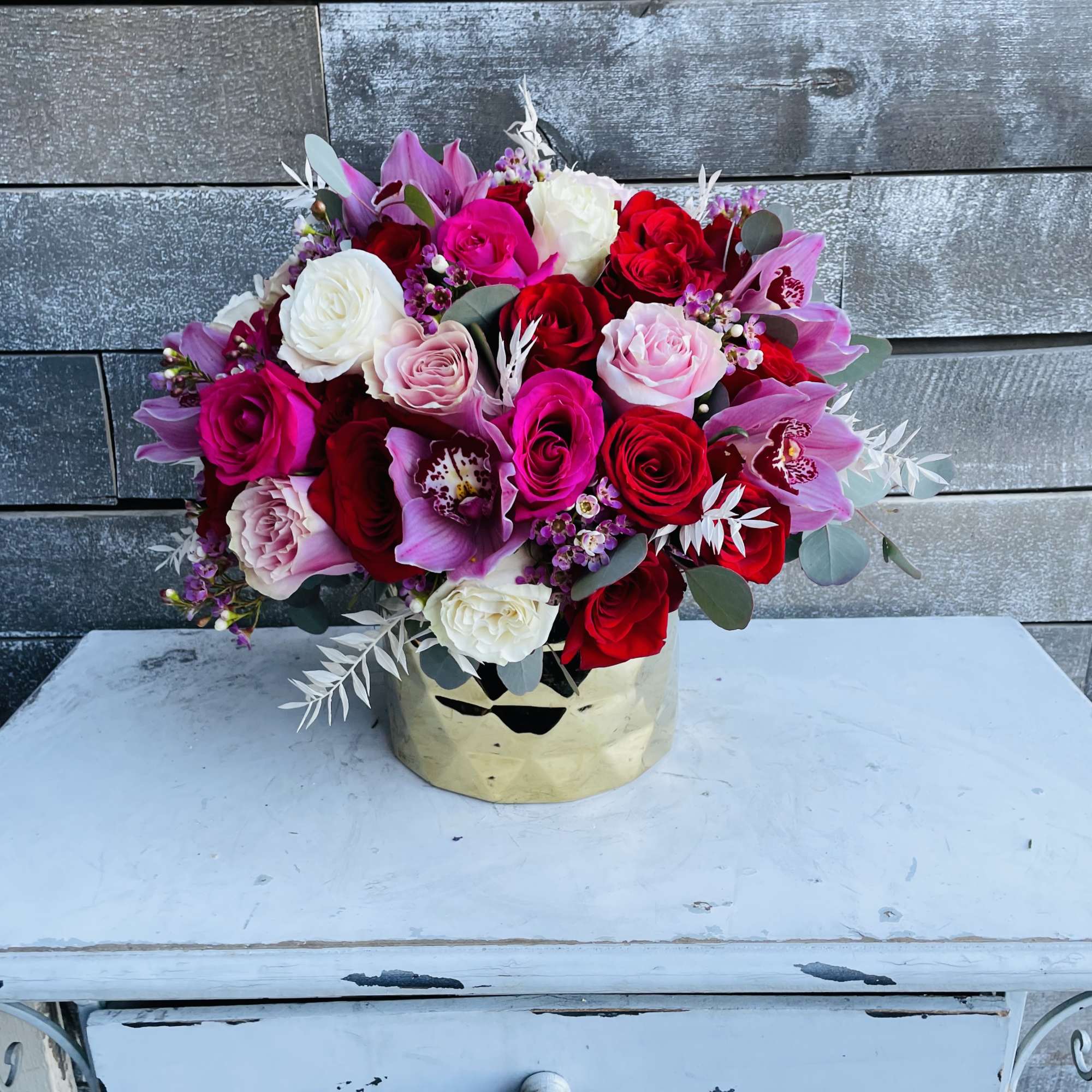 Bouquet of red, pink, and white roses in a gold vase