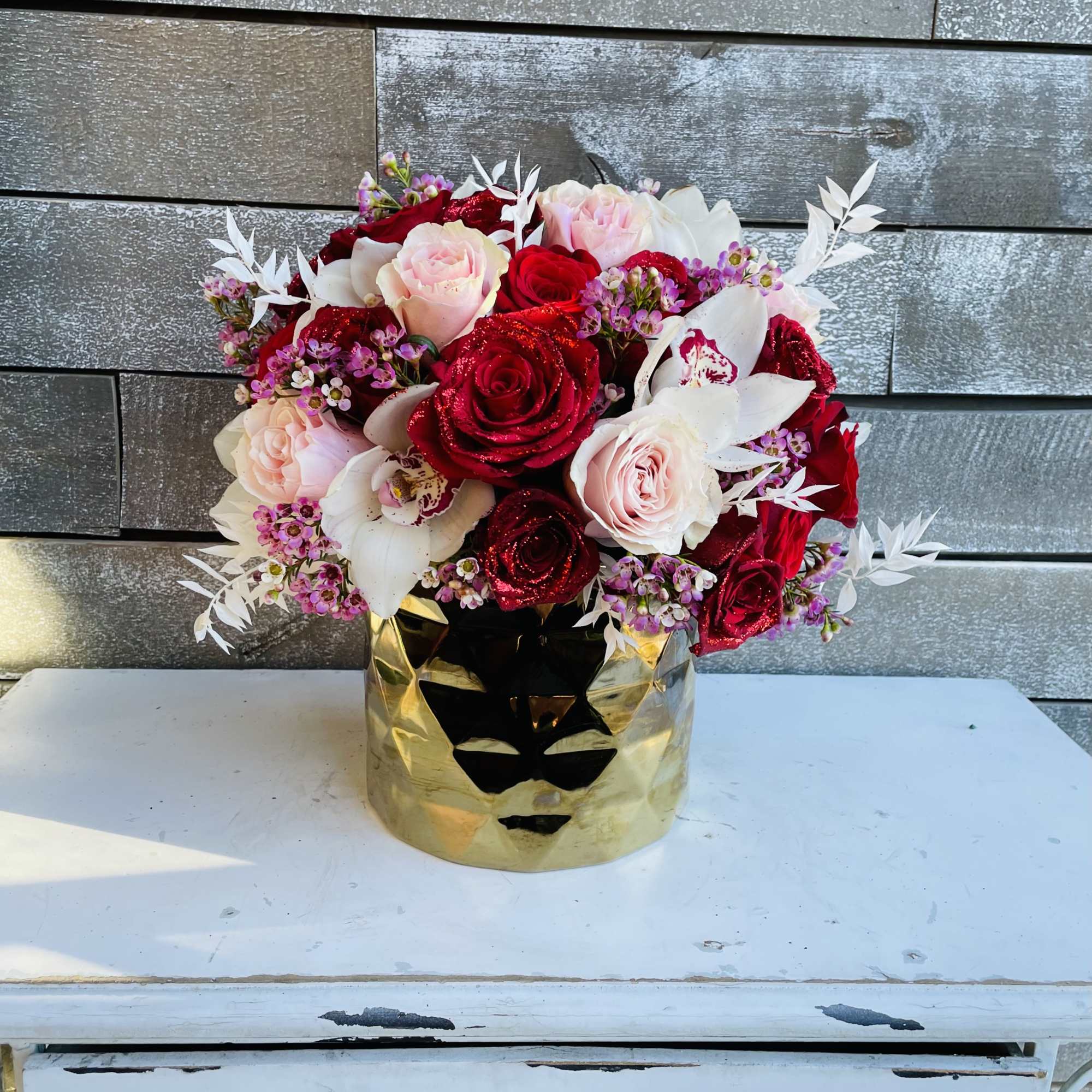 Red and blush roses arranged in a gold vase