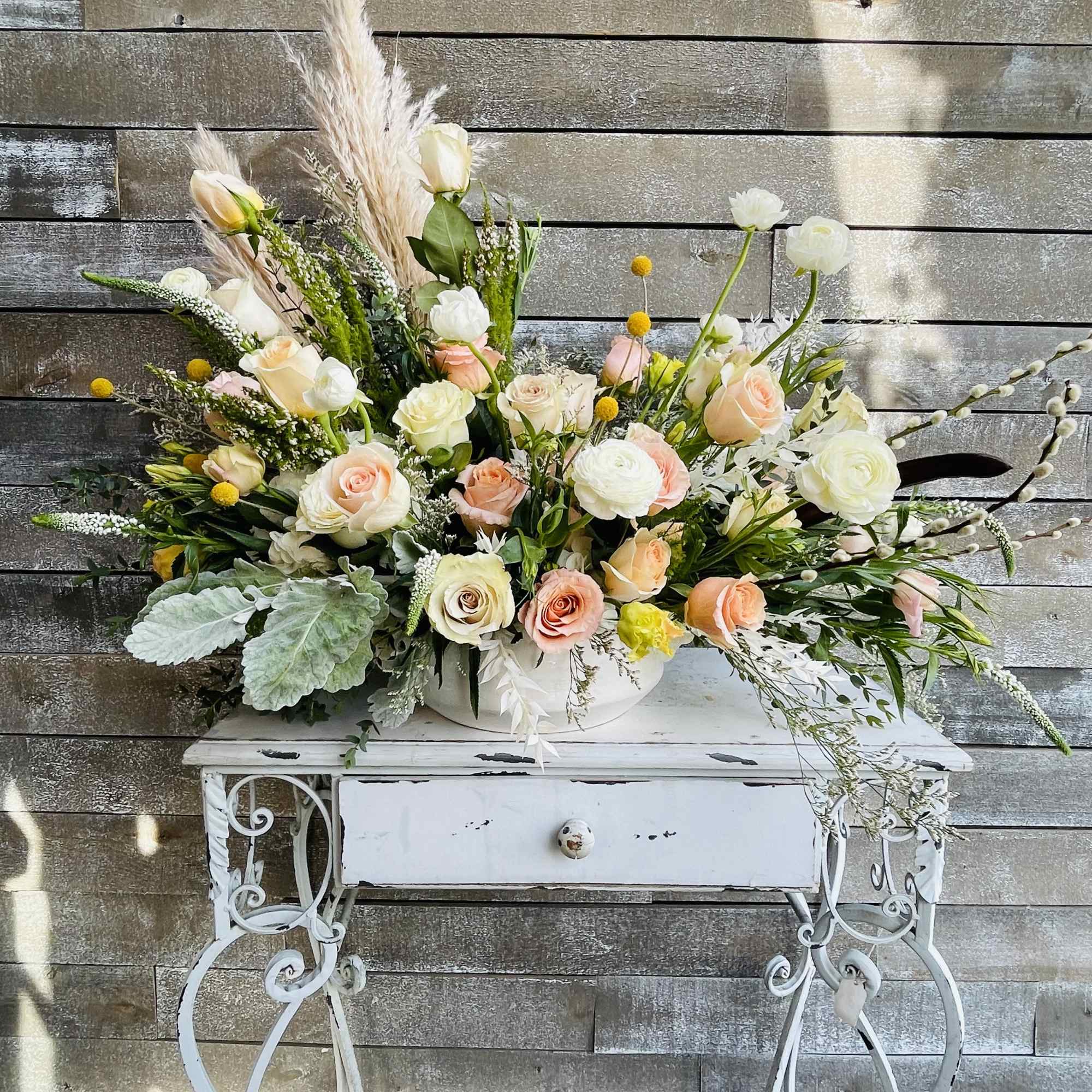 Large pastel floral arrangement in a white container on a decorative table, photo 4 of 6