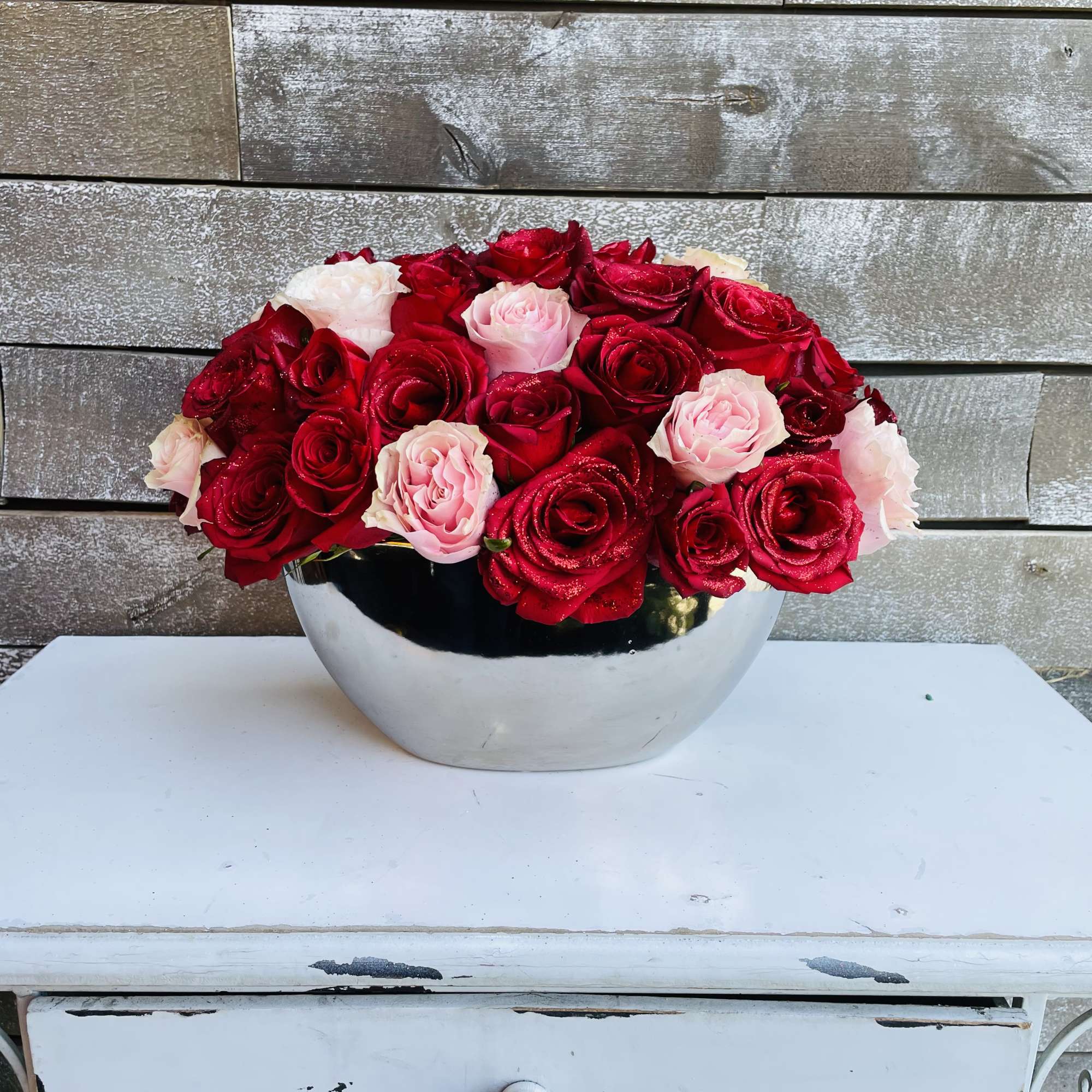 Red and pink roses arranged in a silver bowl