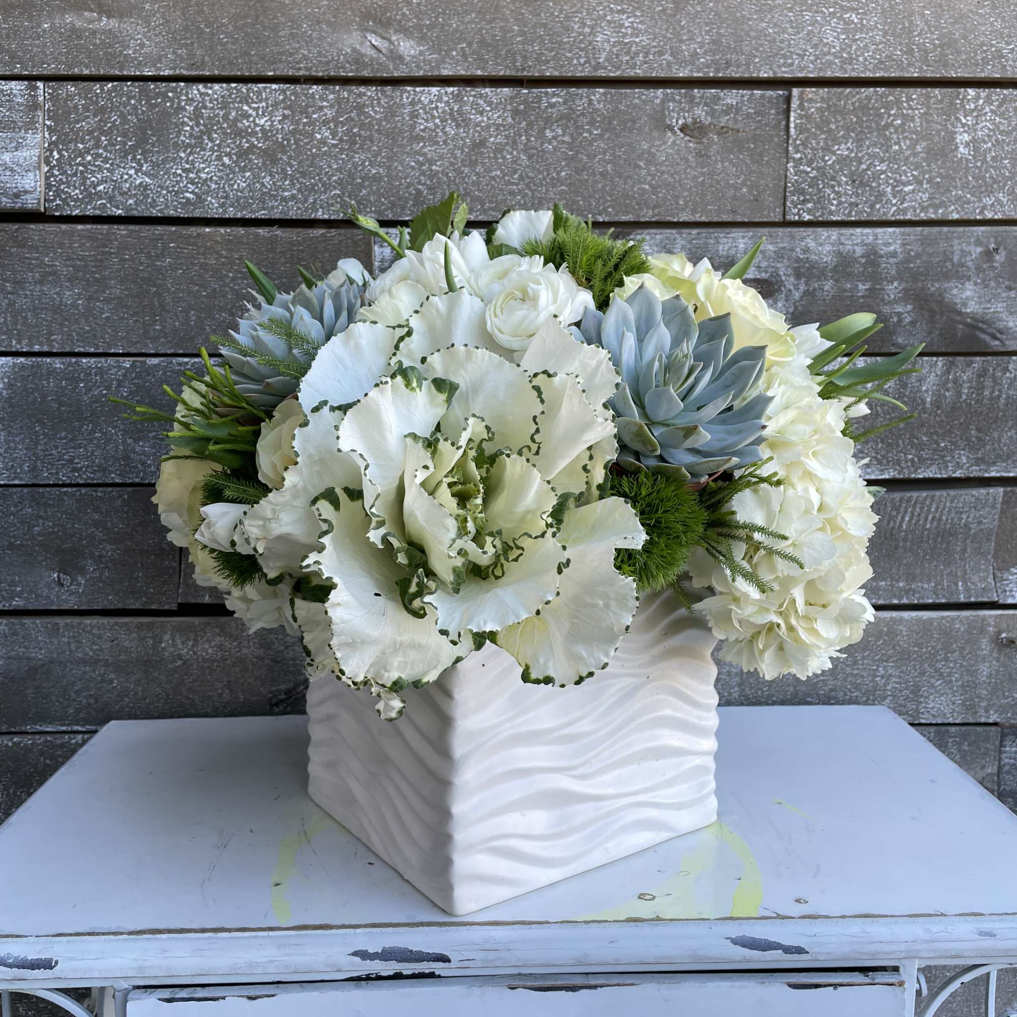 White floral arrangement in a textured square vase
