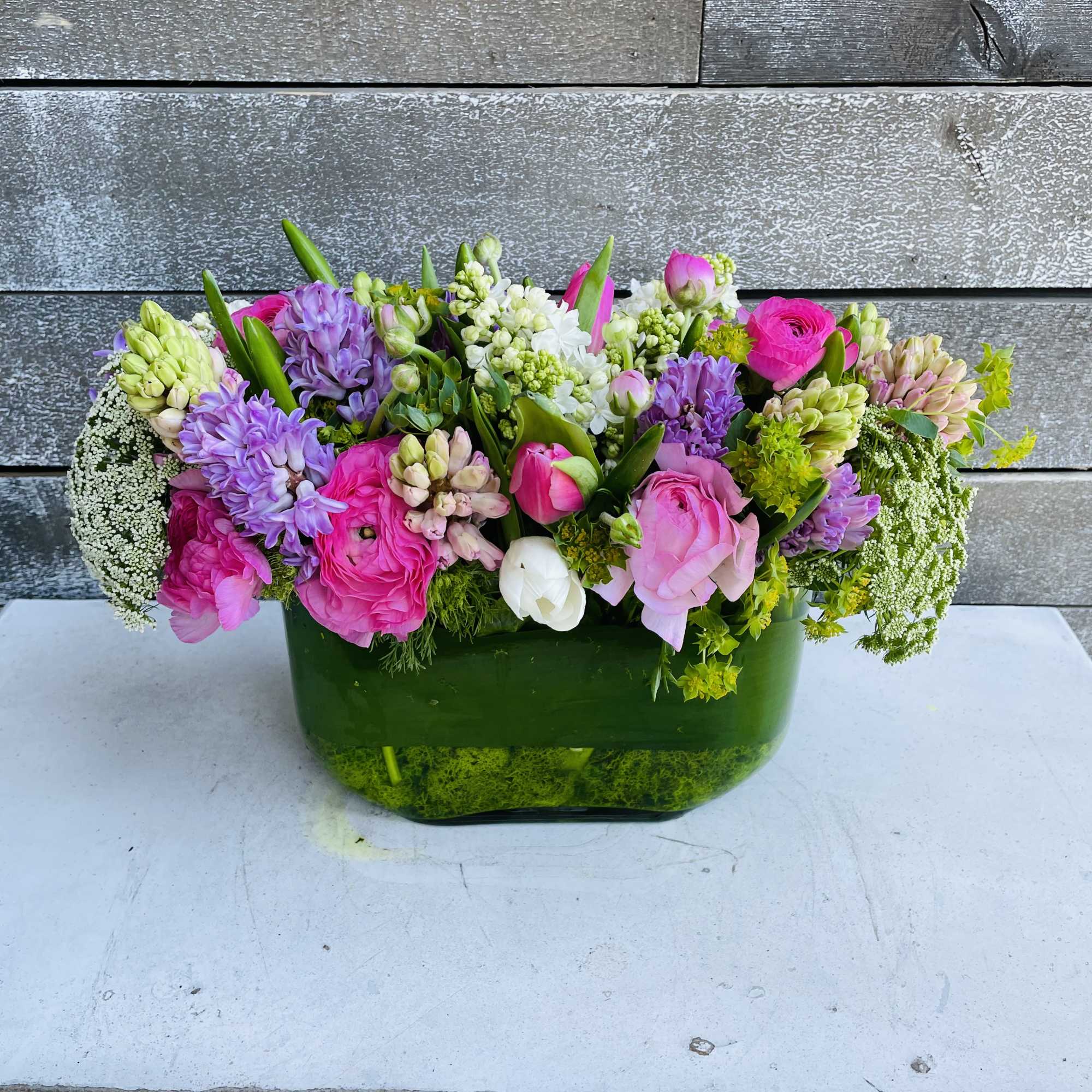 Mixed pink and purple flowers arranged in a green glass vase, photo 3 of 3