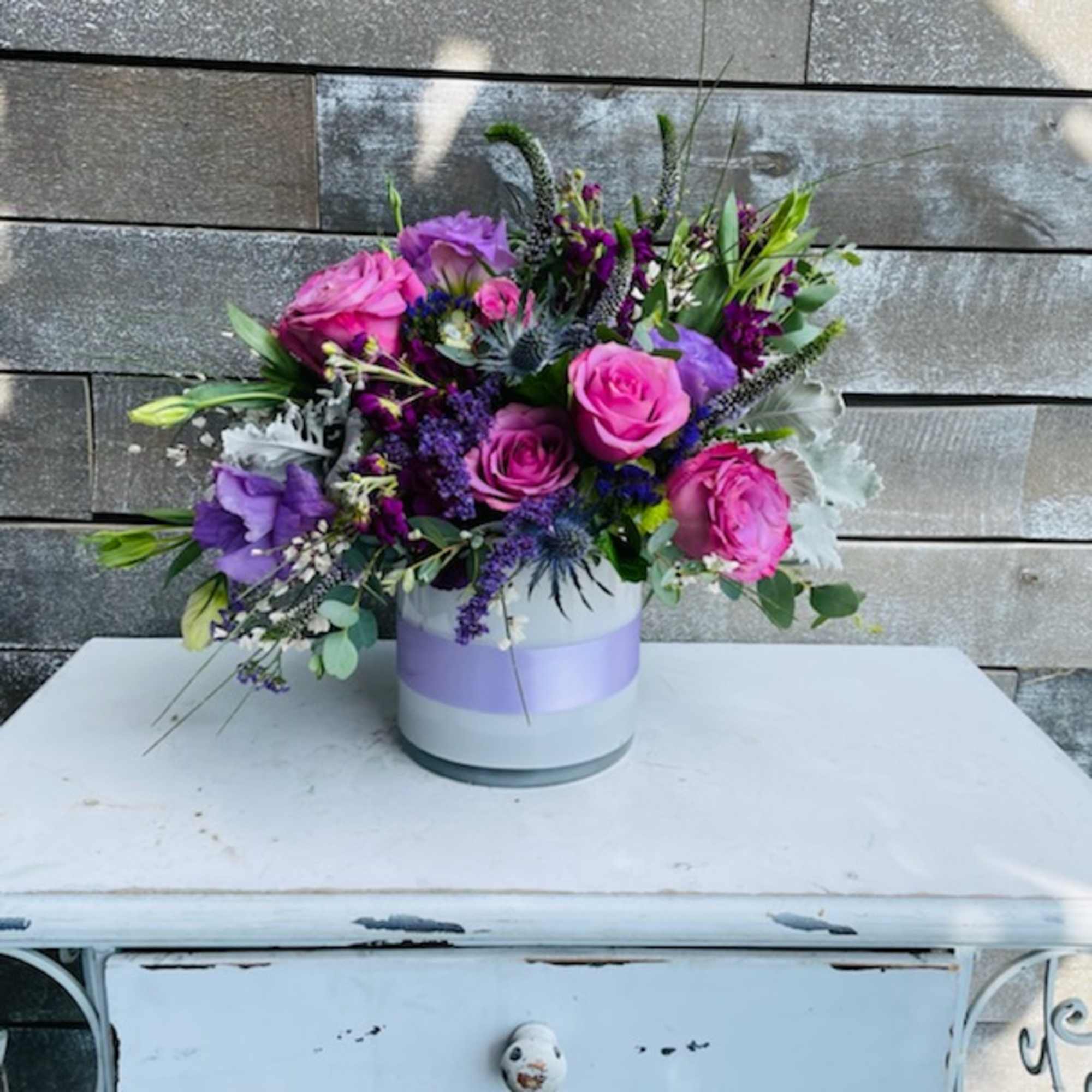 Pink and purple rose arrangement in a round white box