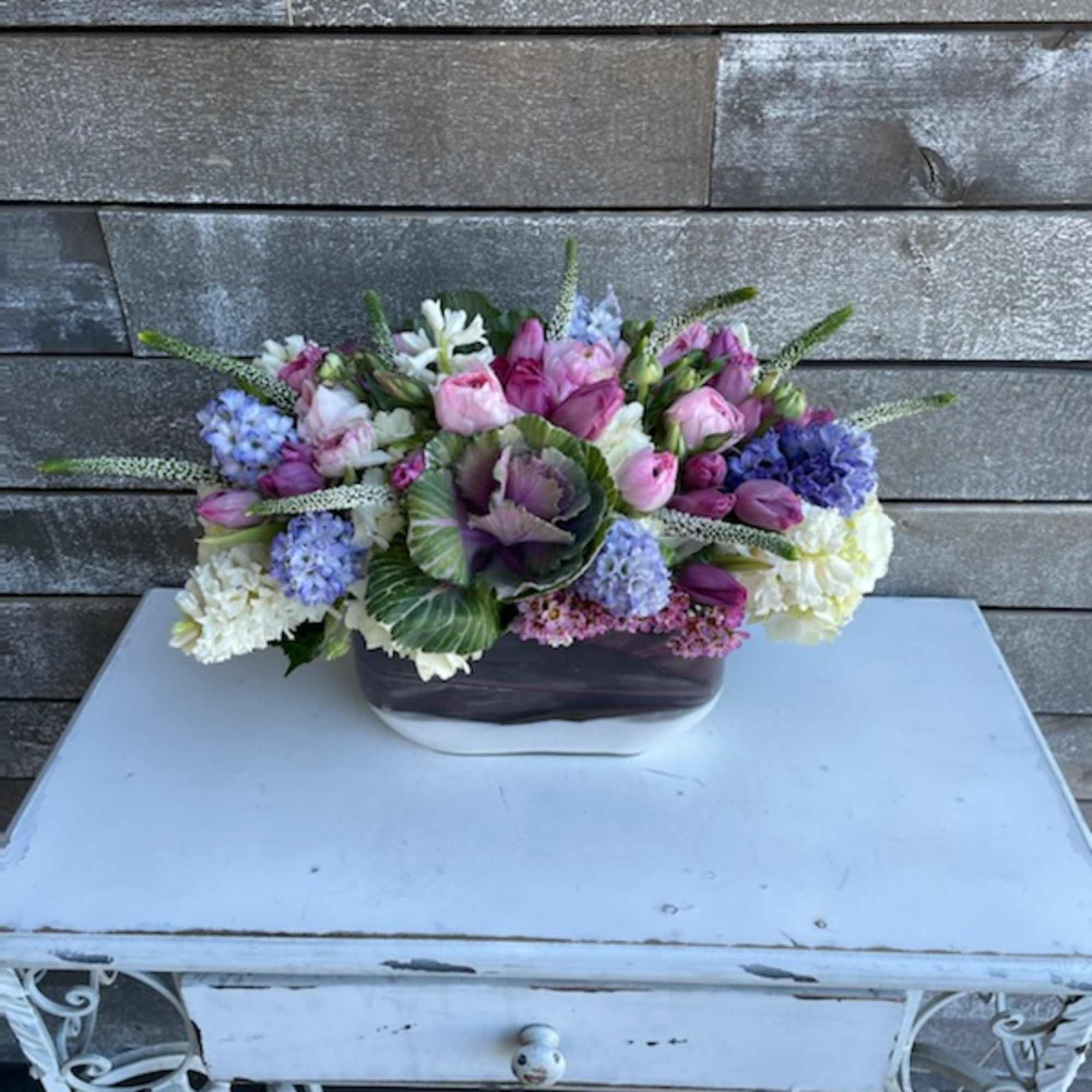 Pink and purple floral arrangement in a low rectangular vase