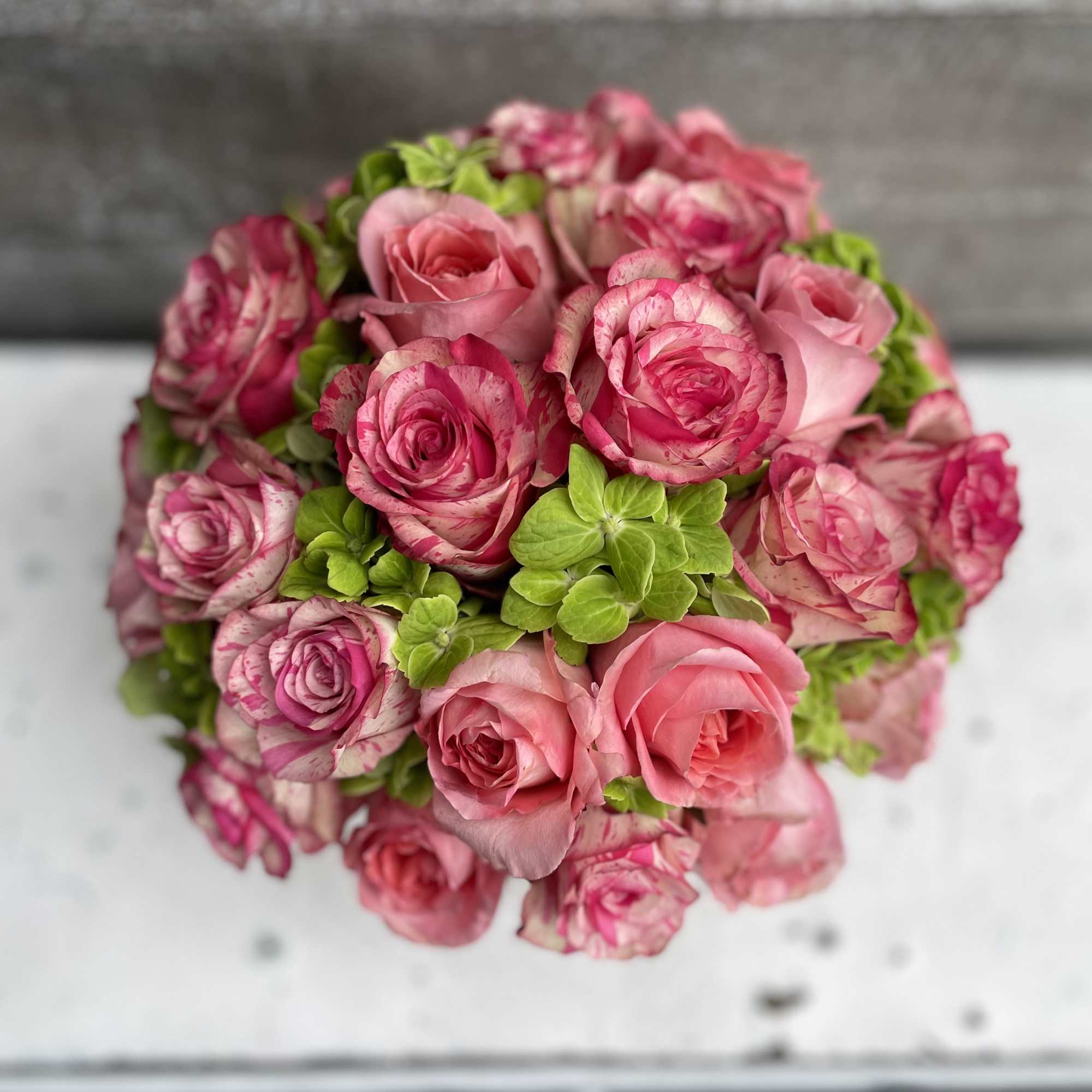 Pink roses arranged in a round bouquet with bright green accents