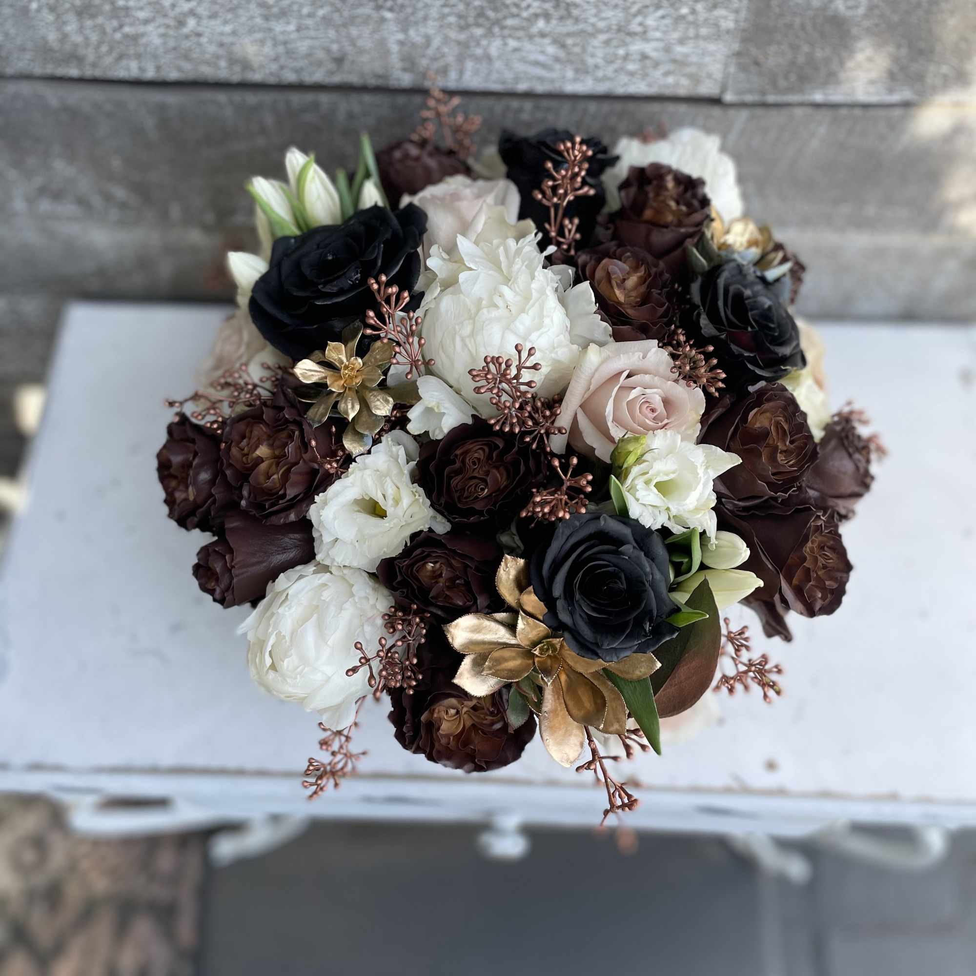 Bouquet of dark and white roses with metallic accents