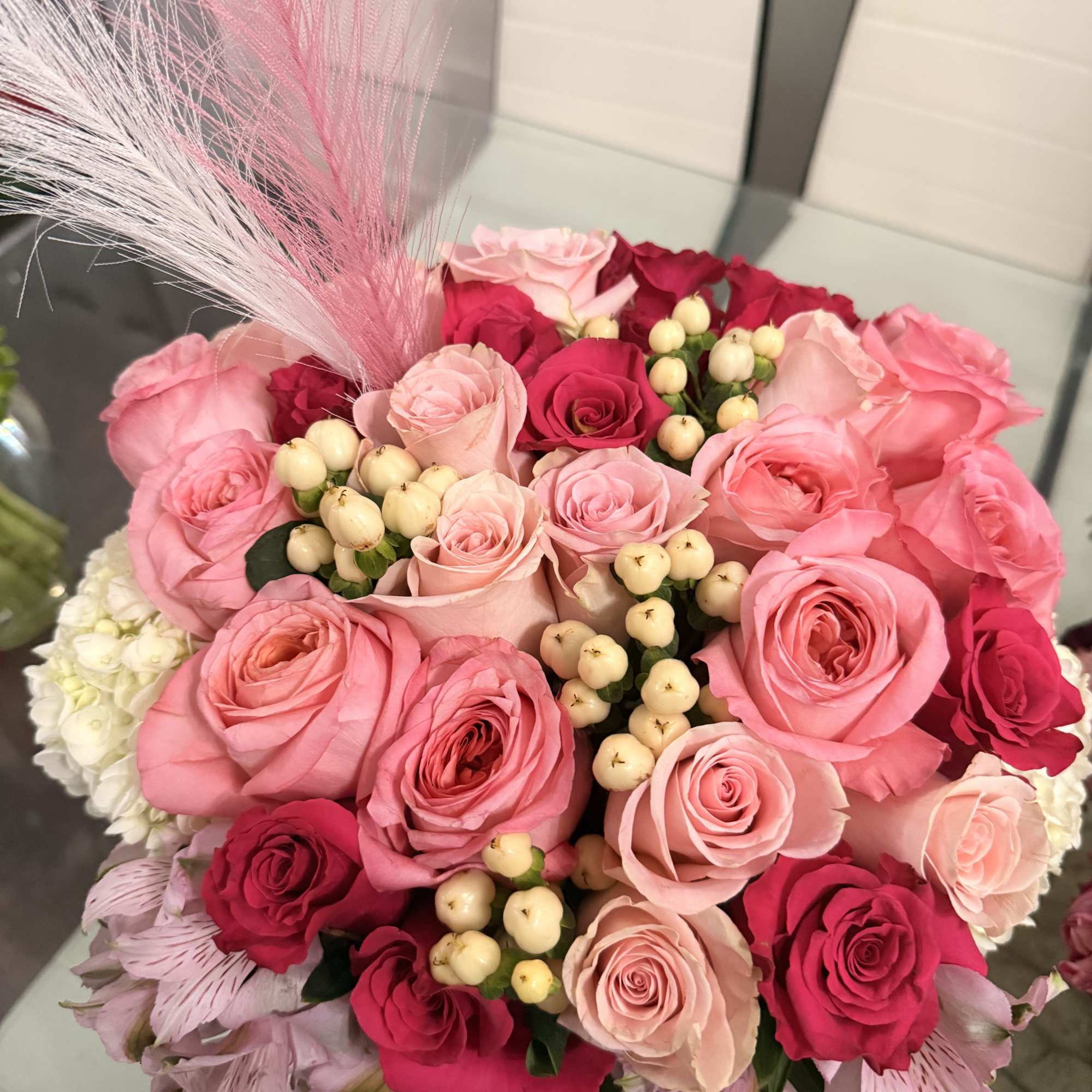 Bouquet of pink and red roses with white berries and pink feathers