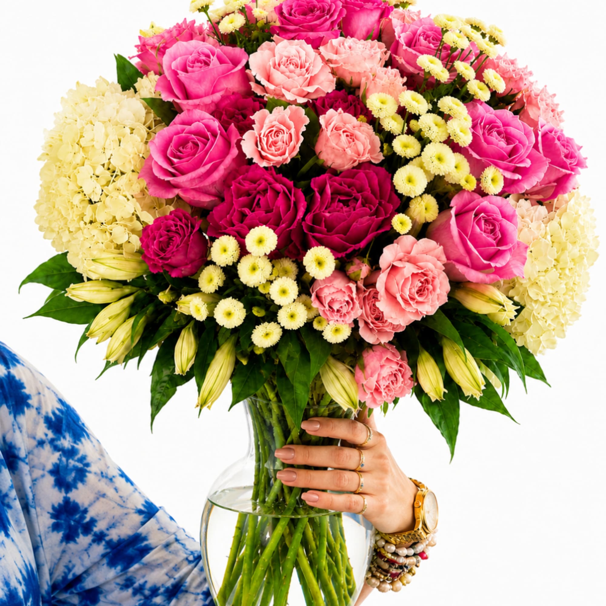 Large bouquet of pink roses, carnations, and pale yellow flowers in a glass vase
