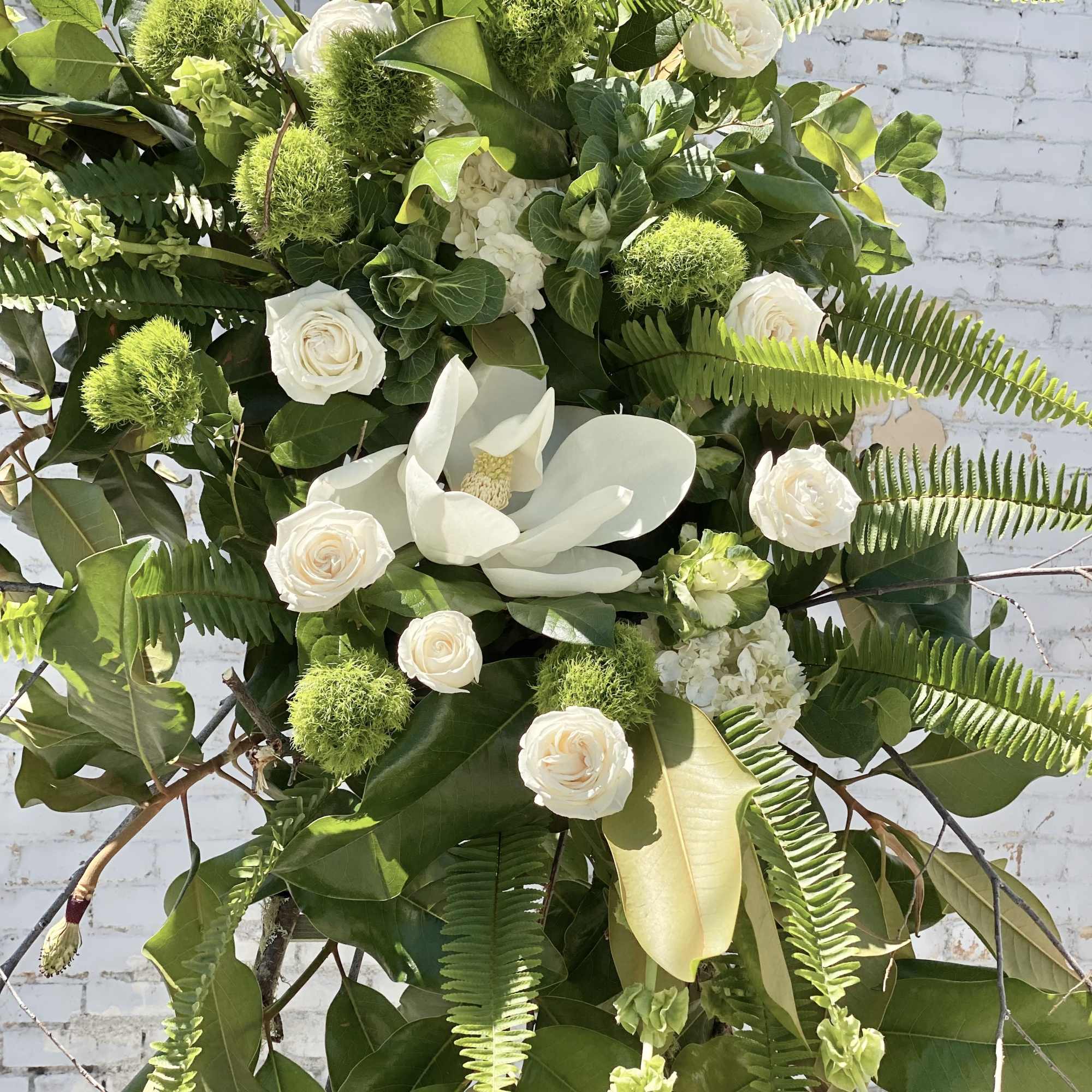 White roses and a white calla lily in a lush green floral spray