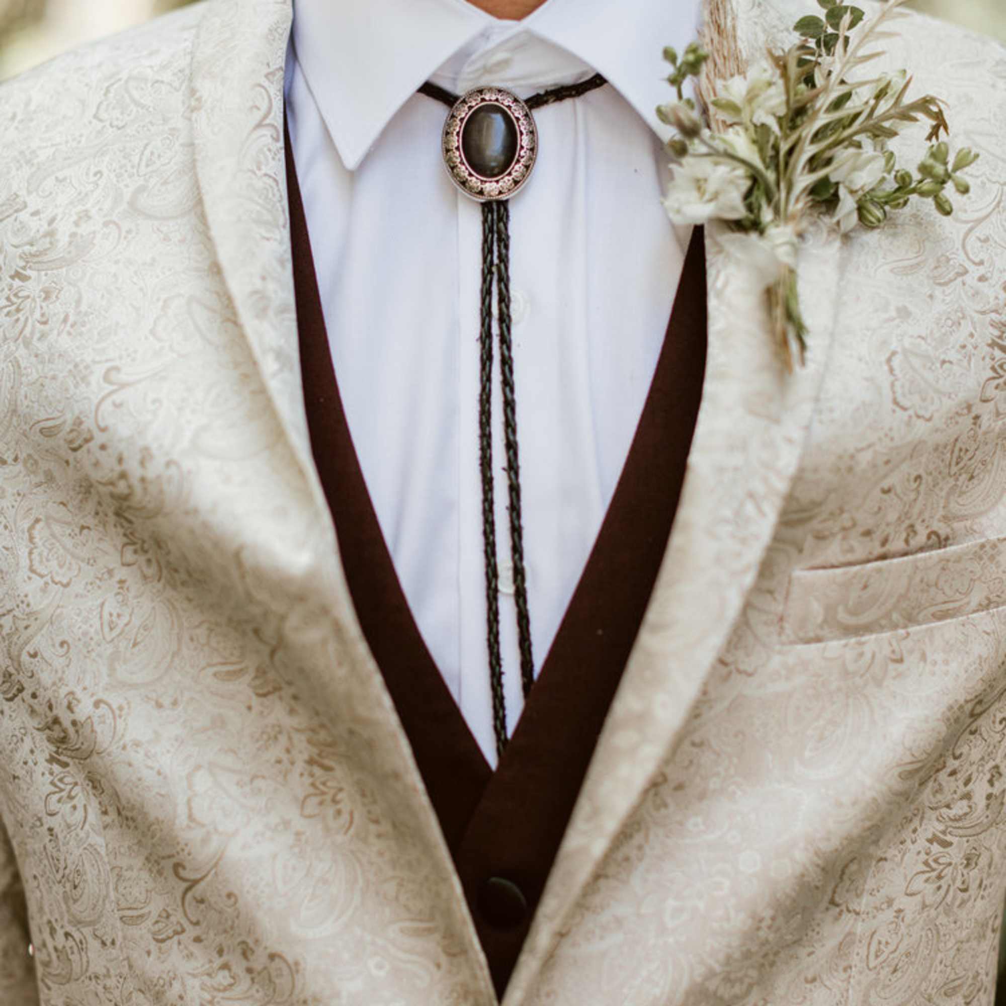 Boutonniere on a cream patterned suit jacket with bolo tie
