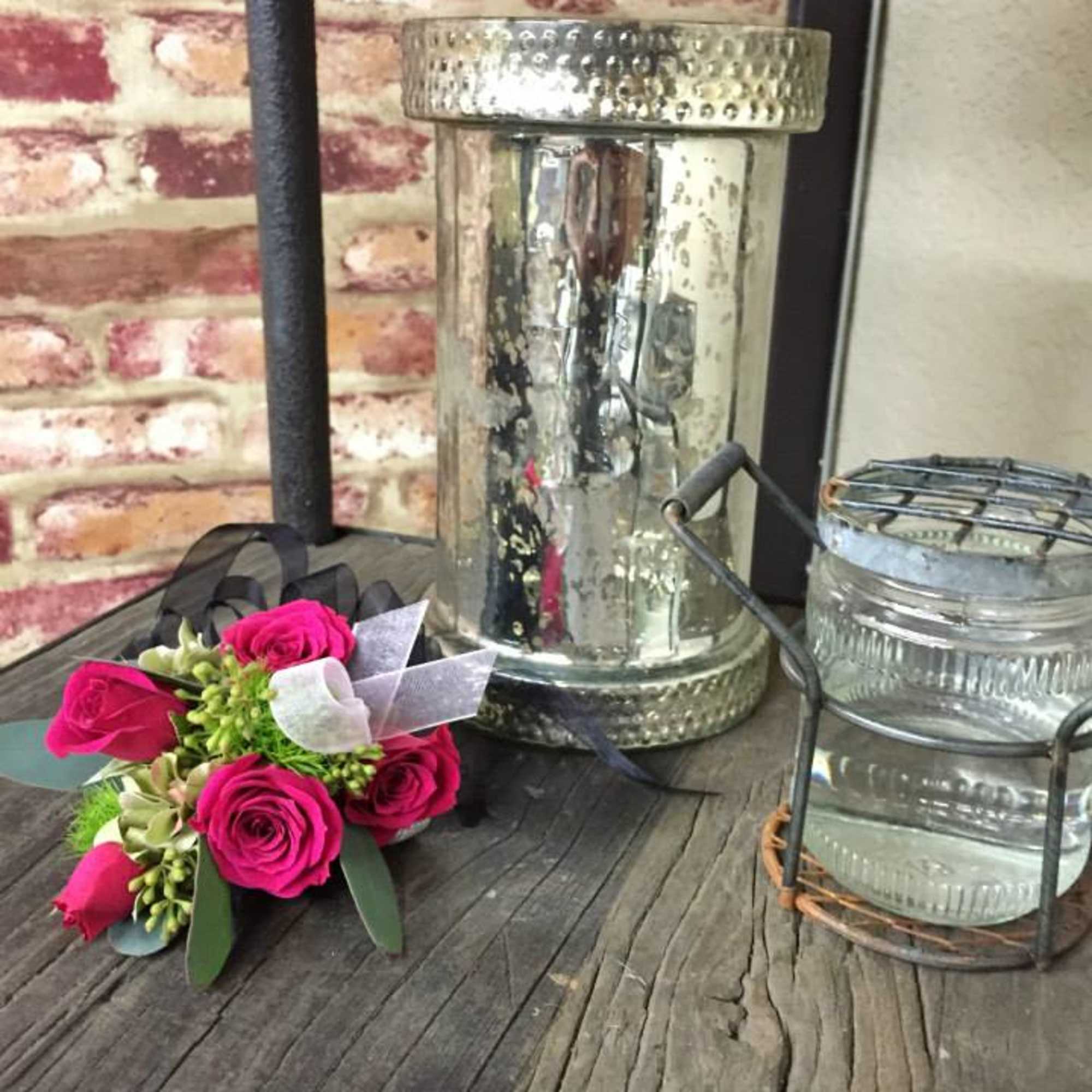 Small bouquet of pink roses with ribbon on a rustic table