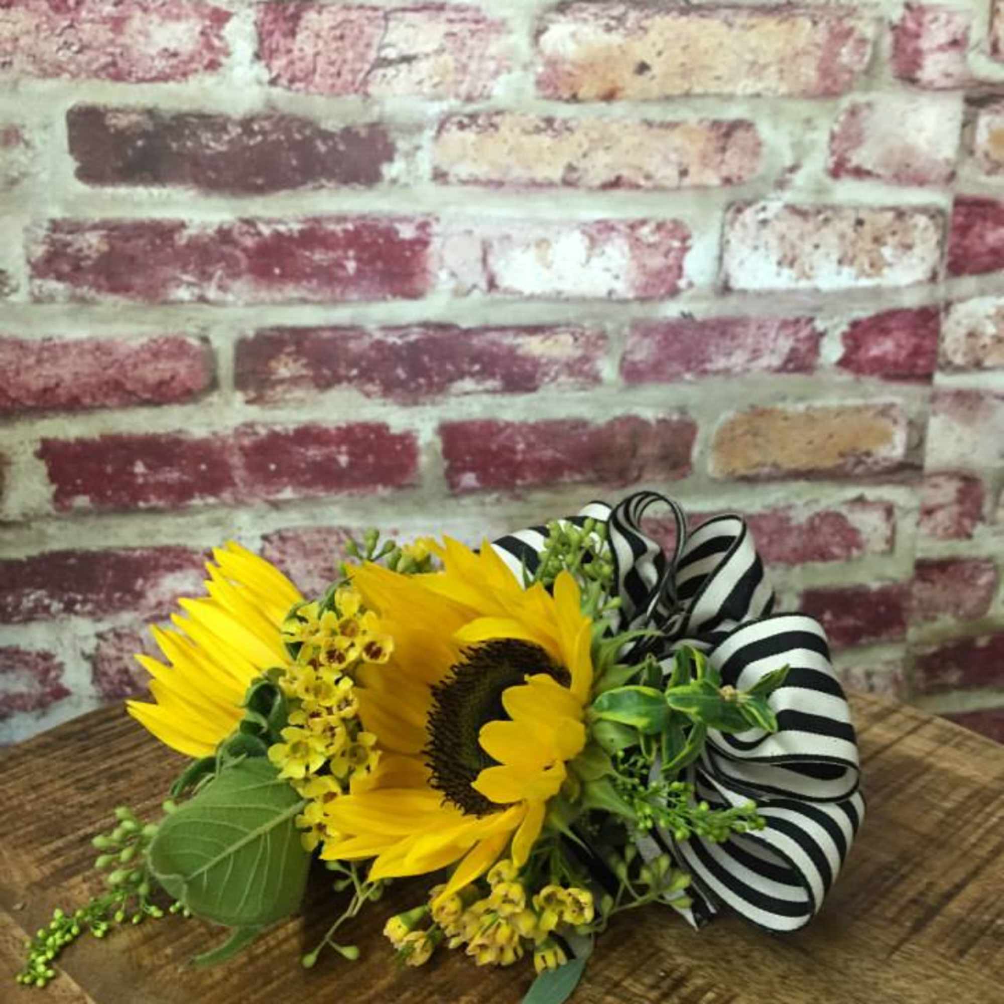 Sunflower bouquet with yellow filler flowers and a black-and-white striped ribbon
